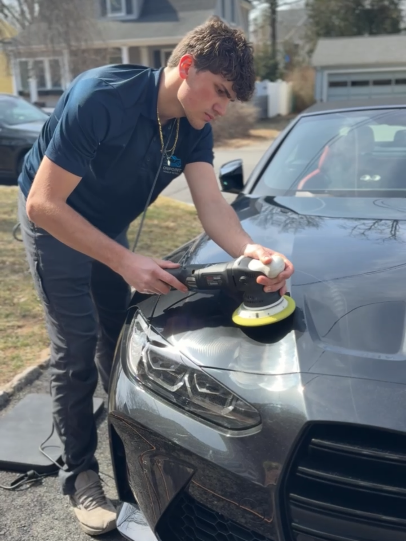 A young man is polishing the front of a car