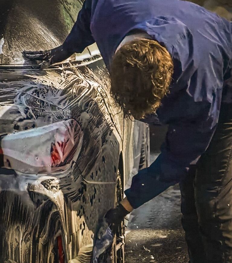 A man is washing a car with soap and water
