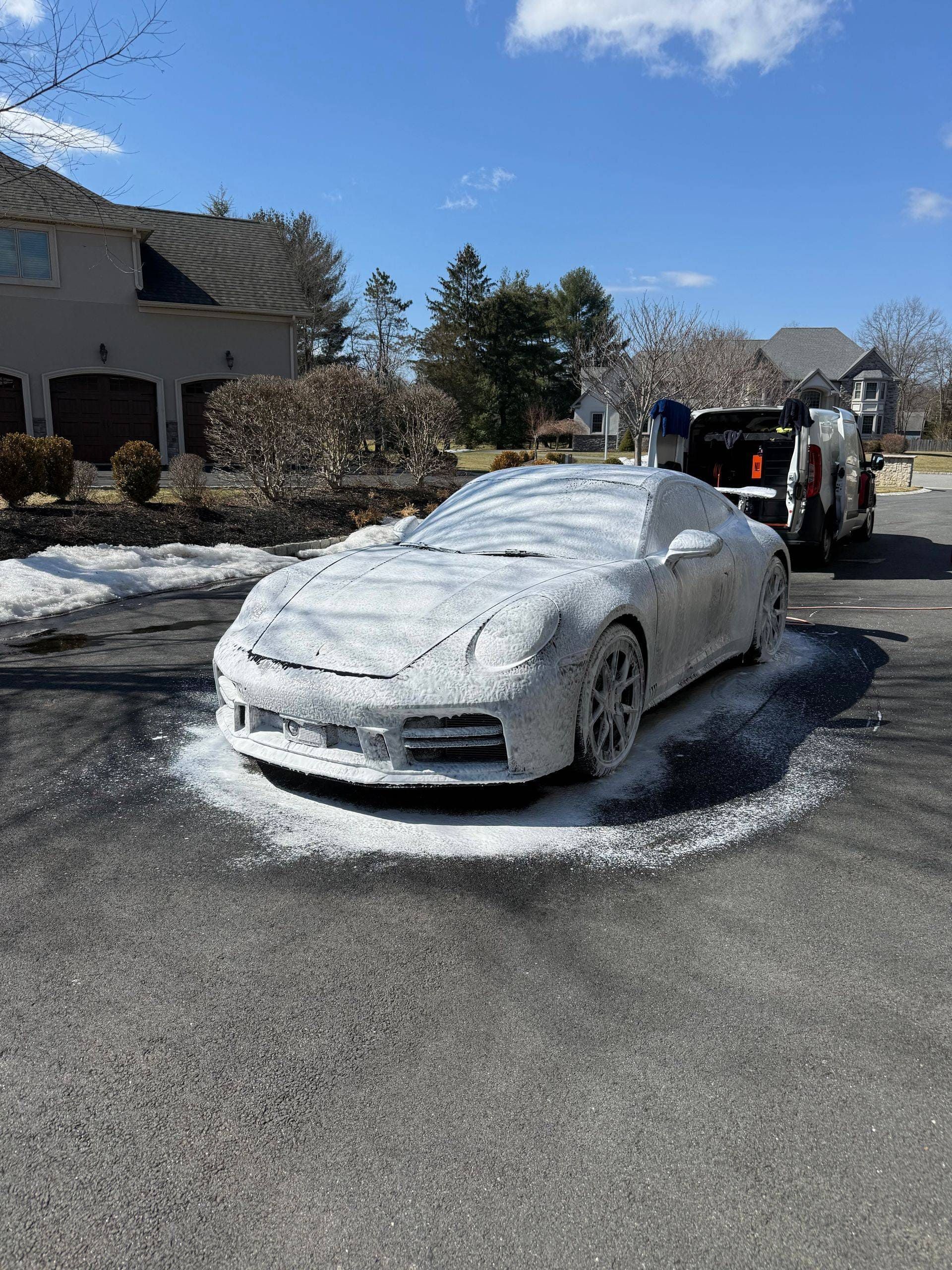 Car completely covered in snow on a residential street with a tow truck behind it