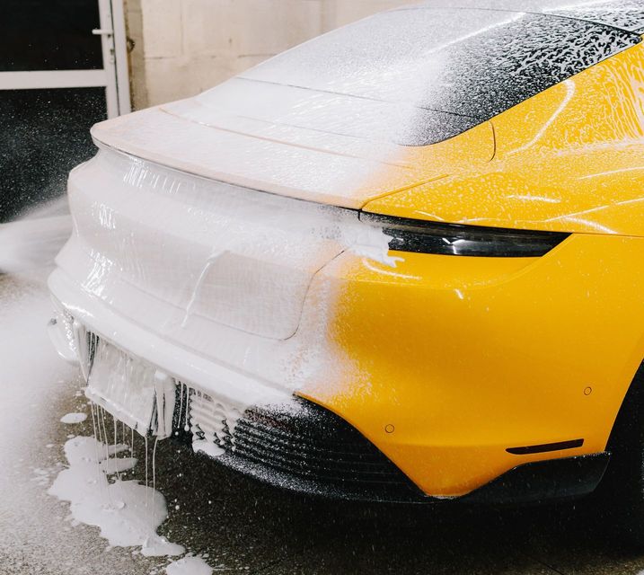 A car is being washed with foam in a garage.
