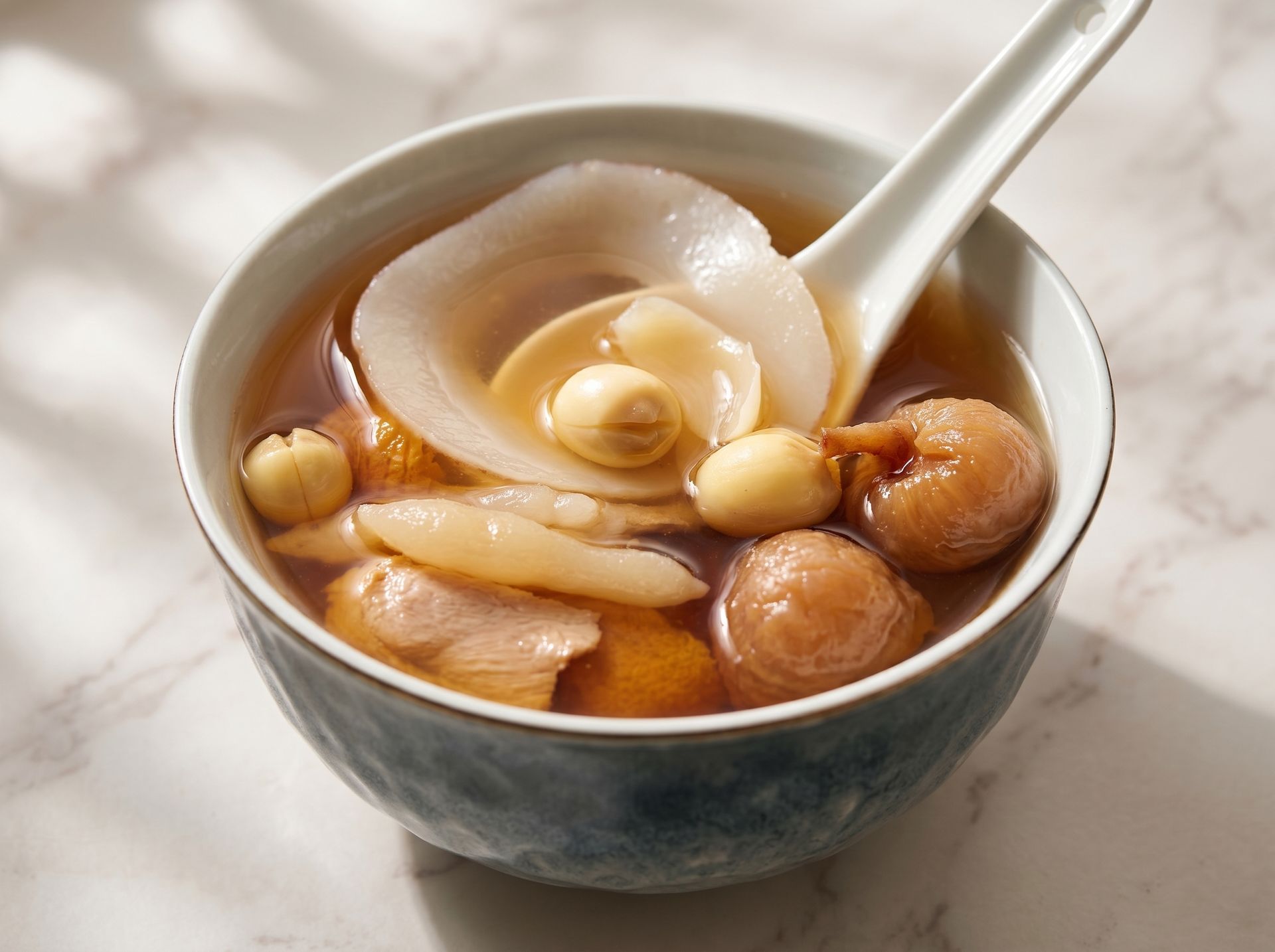 Bowl of sweet soup with dumplings, peanuts, and a white spoon
