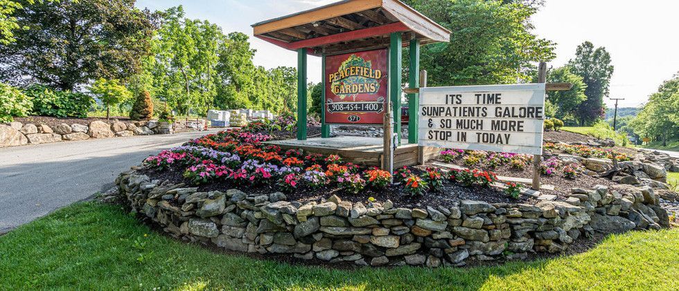 Stone garden sign with flowers at the entrance to the Irish Setter Club, surrounded by trees and rocks