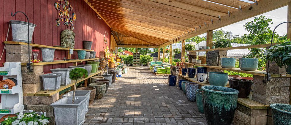 Covered outdoor garden market aisle with rows of colorful planters and pots
