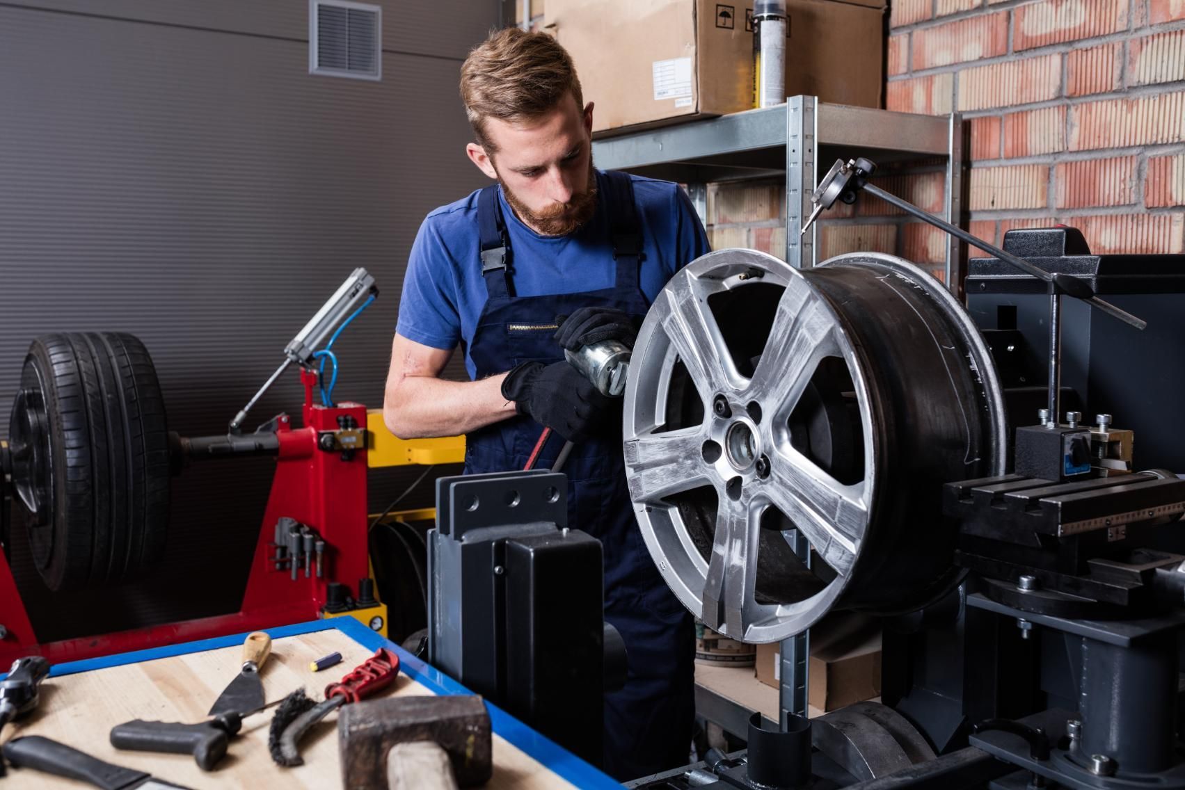 A man is working on a wheel in a garage.