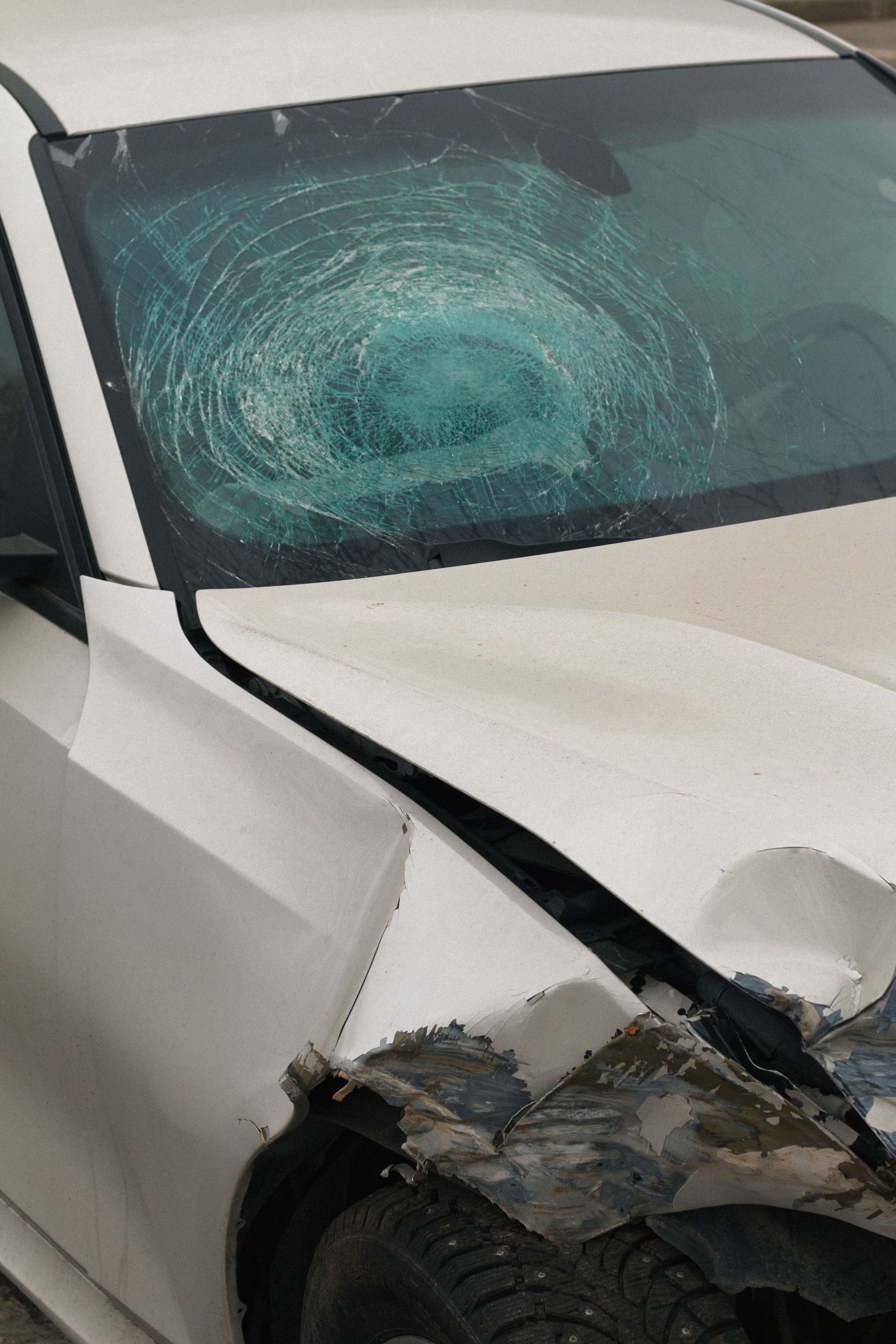 A man is working on a white car with a hammer.