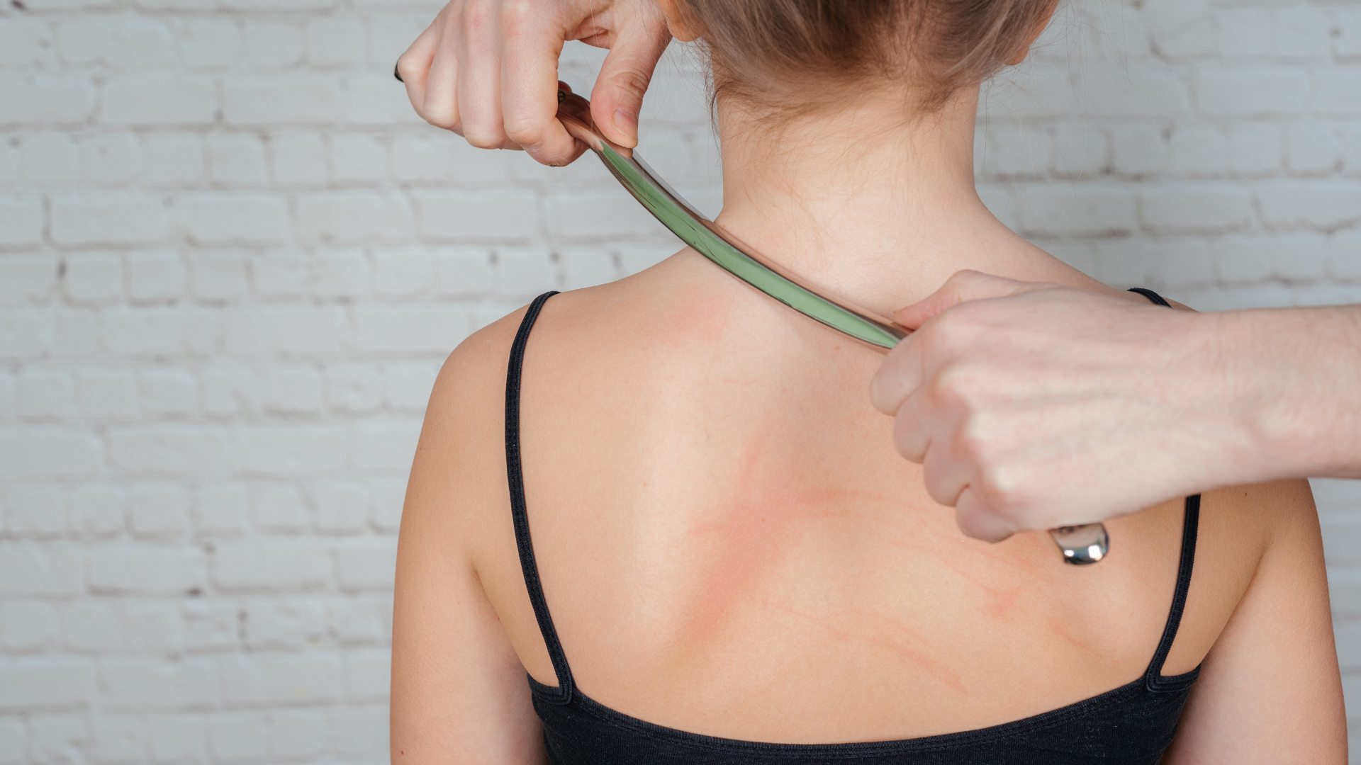 Hands using a green tape measure across a person’s upper back and shoulder blades