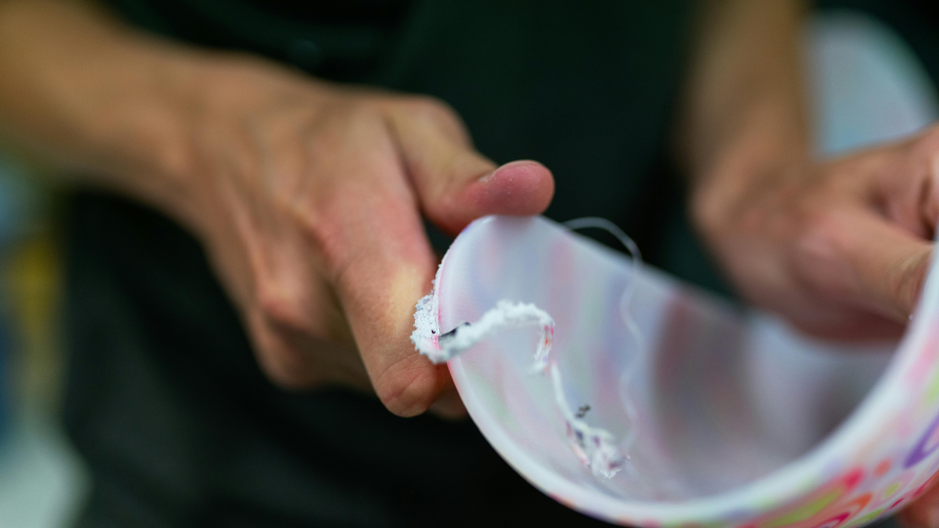 Hands holding a translucent, curved plastic sheet with white trim against a blurred background