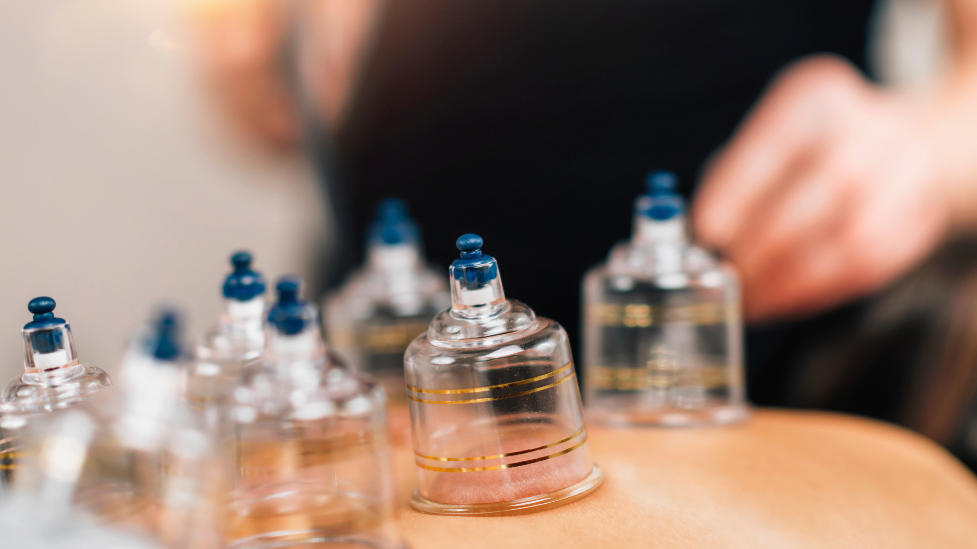 Glass cupping cups on a wooden table, with blurred hands in the background