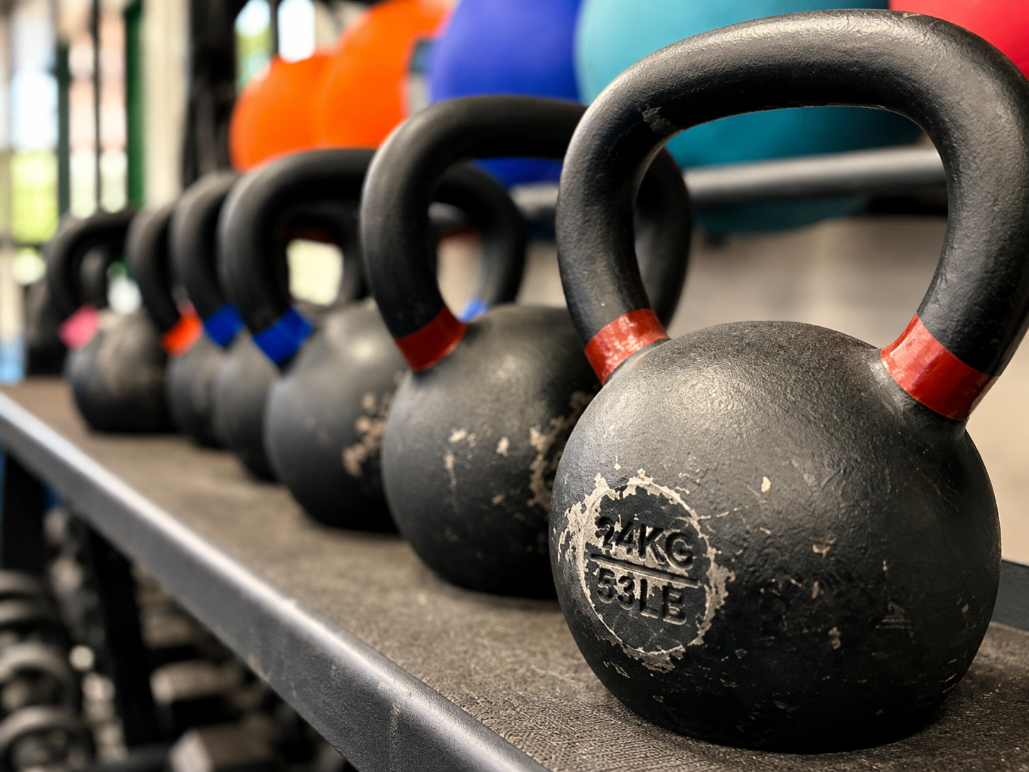 Row of black kettlebells with red accents on a gym rack