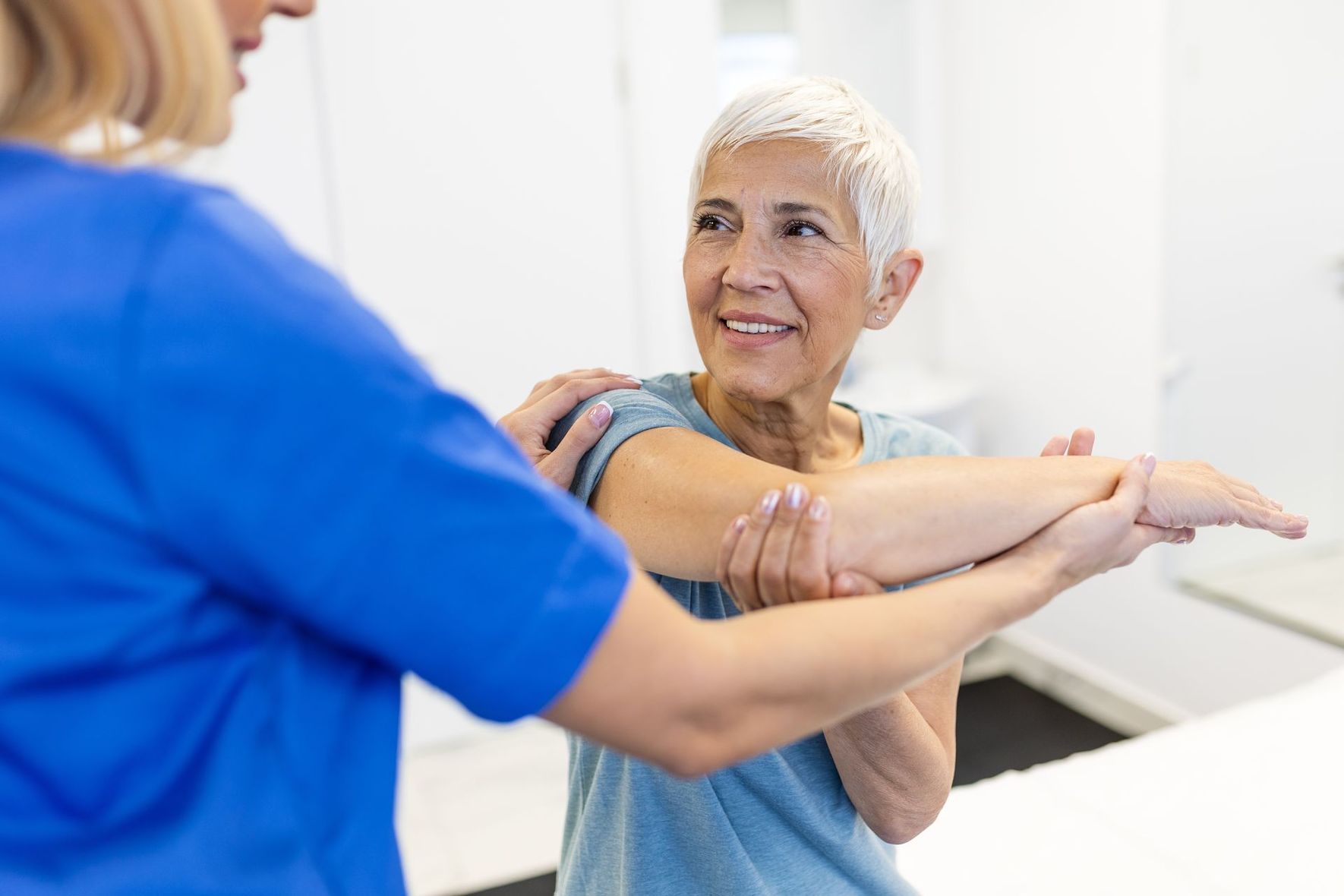 Physical therapist assisting a patient with a leg stretch in a bright clinic room