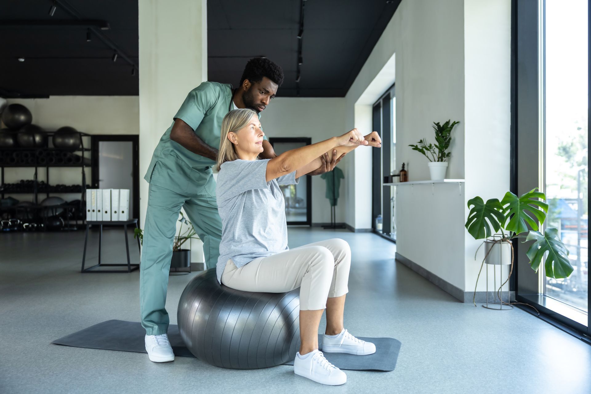 Two people training in a gym, swinging a weighted cable from opposite sides.