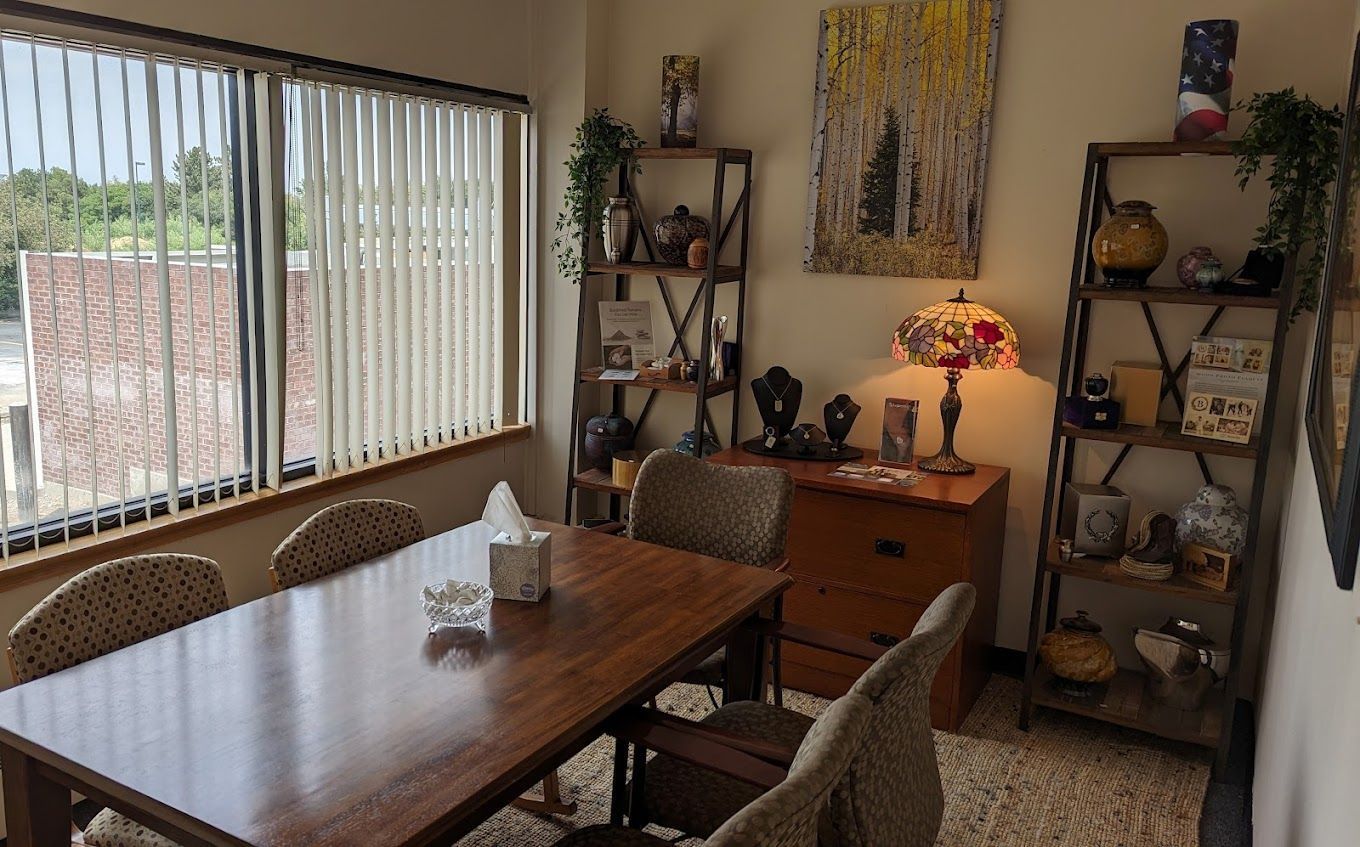 Dining room with wooden table, woven chairs, wall art, and a small lit lamp by the window.