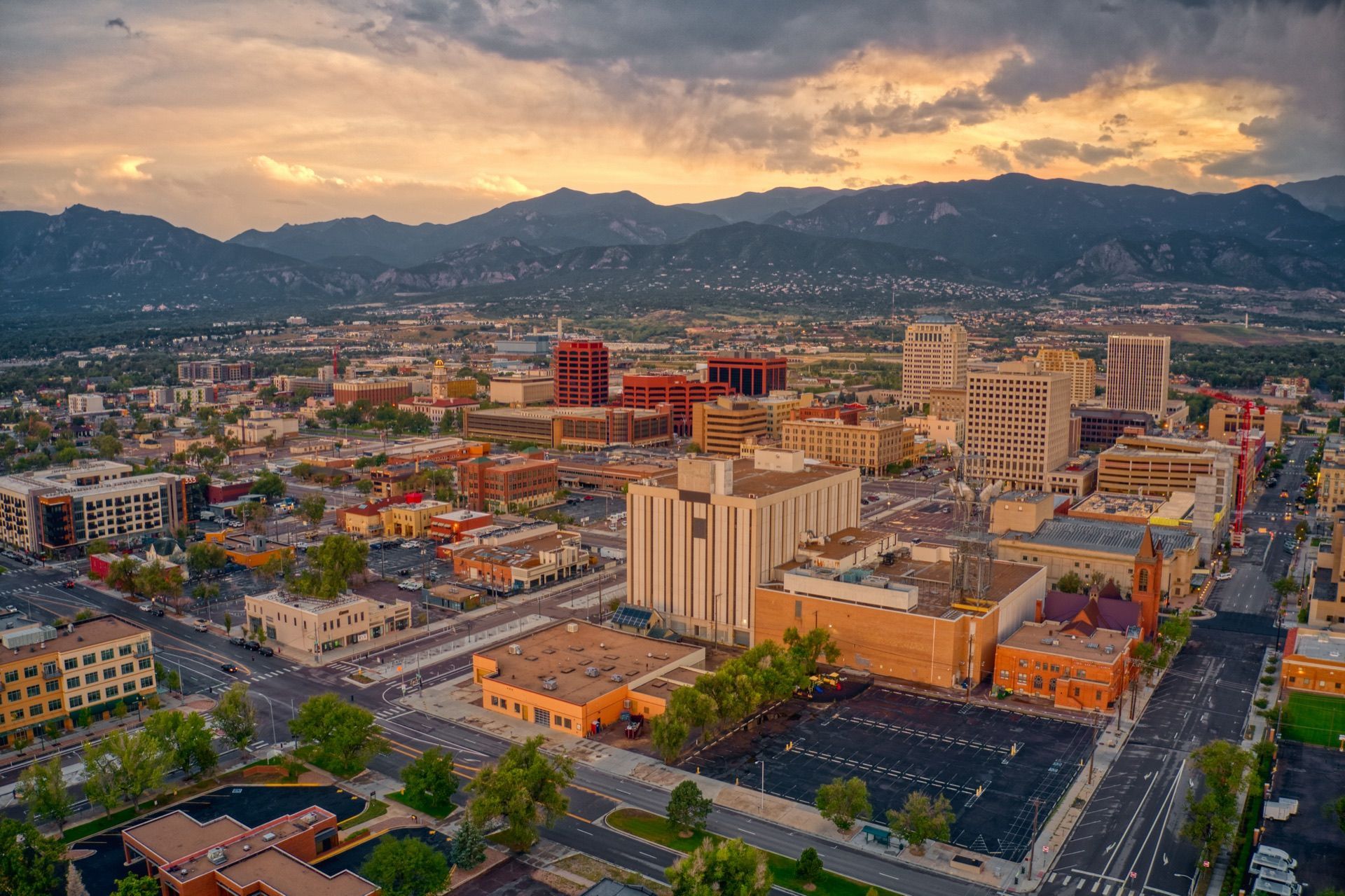 Aerial view of a city skyline at sunset with mountains in the distance