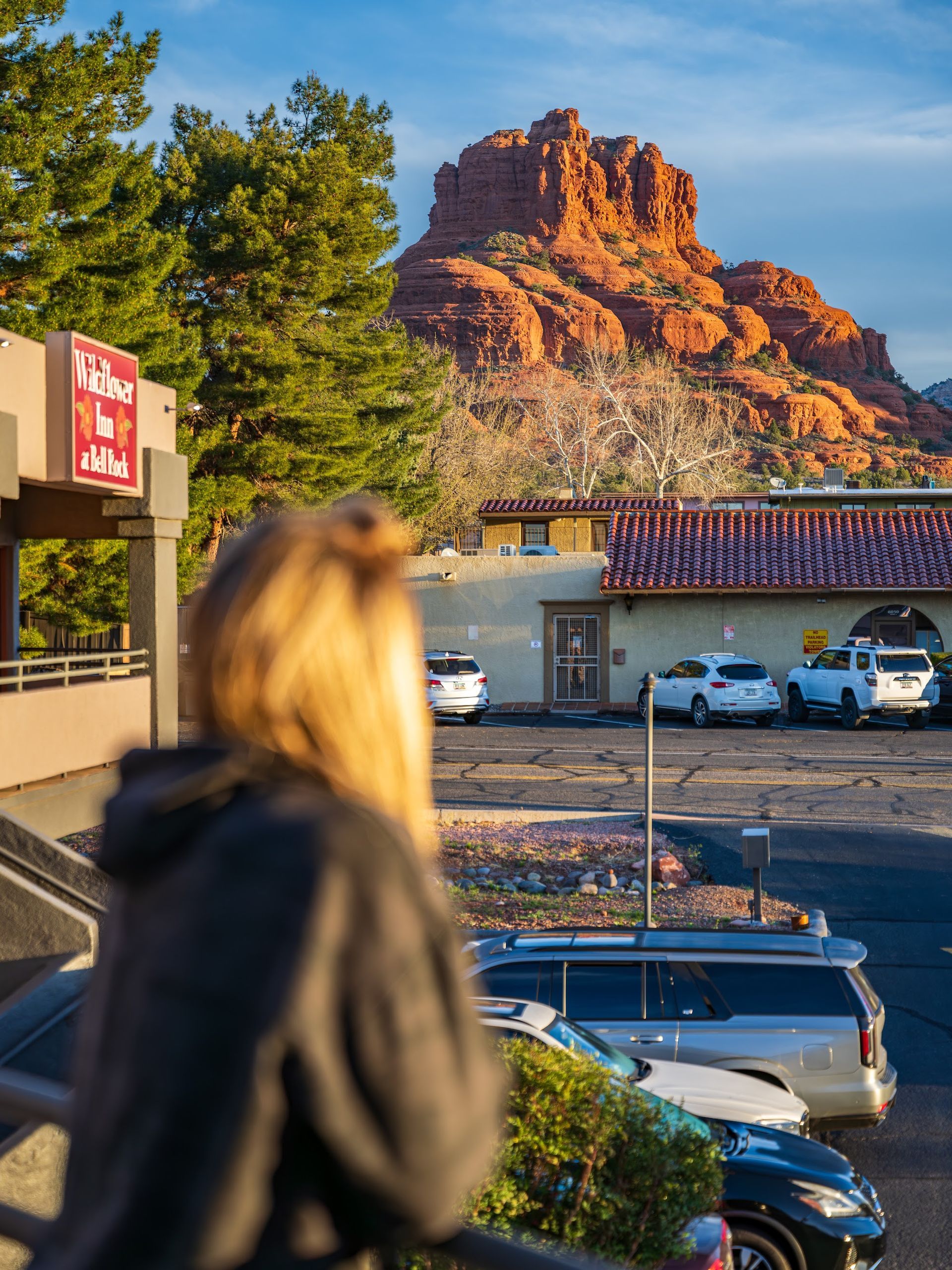 Guest pausing beside the Wildflower Inn at Bell Rock sign with Bell Rock and red rock scenery in the background in Sedona