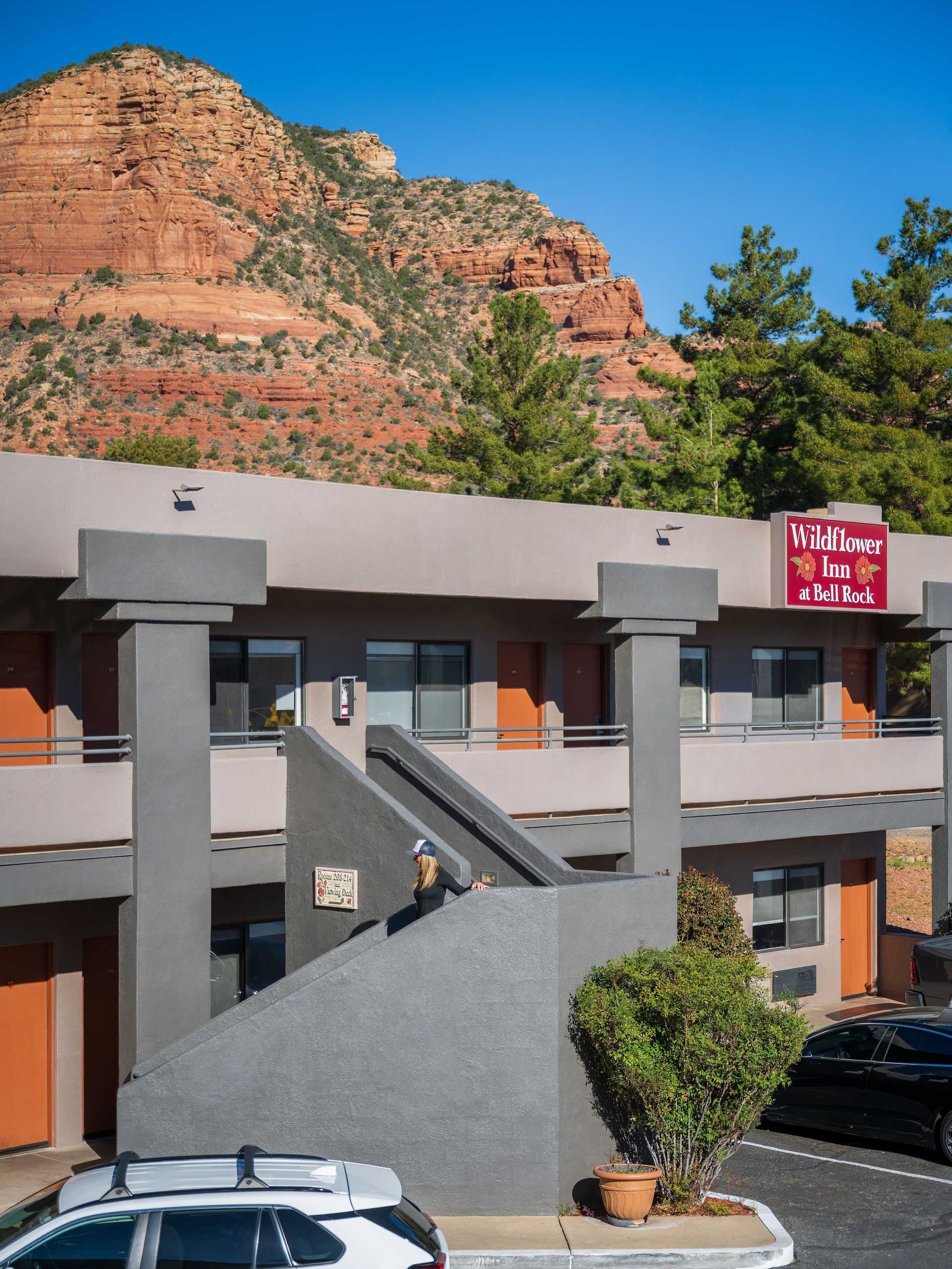 Guests walking along the outdoor stairway at Wildflower Inn at Bell Rock with red rock cliffs behind the property in Sedona