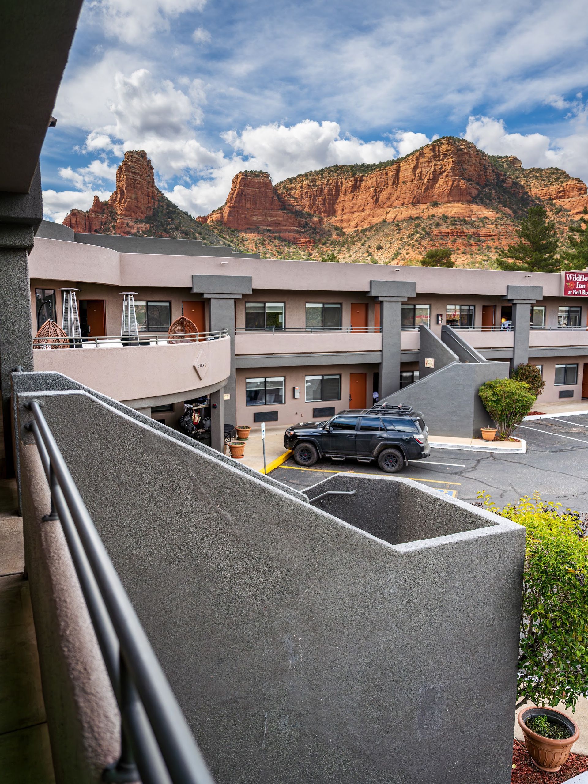 Red rock cliffs rising directly behind the balconies and rooflines of Wildflower Inn at Bell Rock in Village of Oak Creek