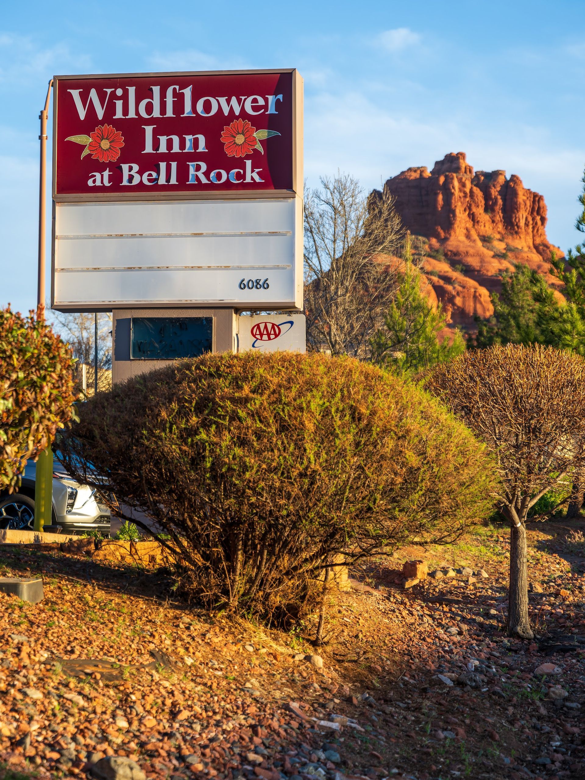 The Wildflower Inn at Bell Rock roadside sign on Highway 179 with red rock formations rising in the background in Sedona