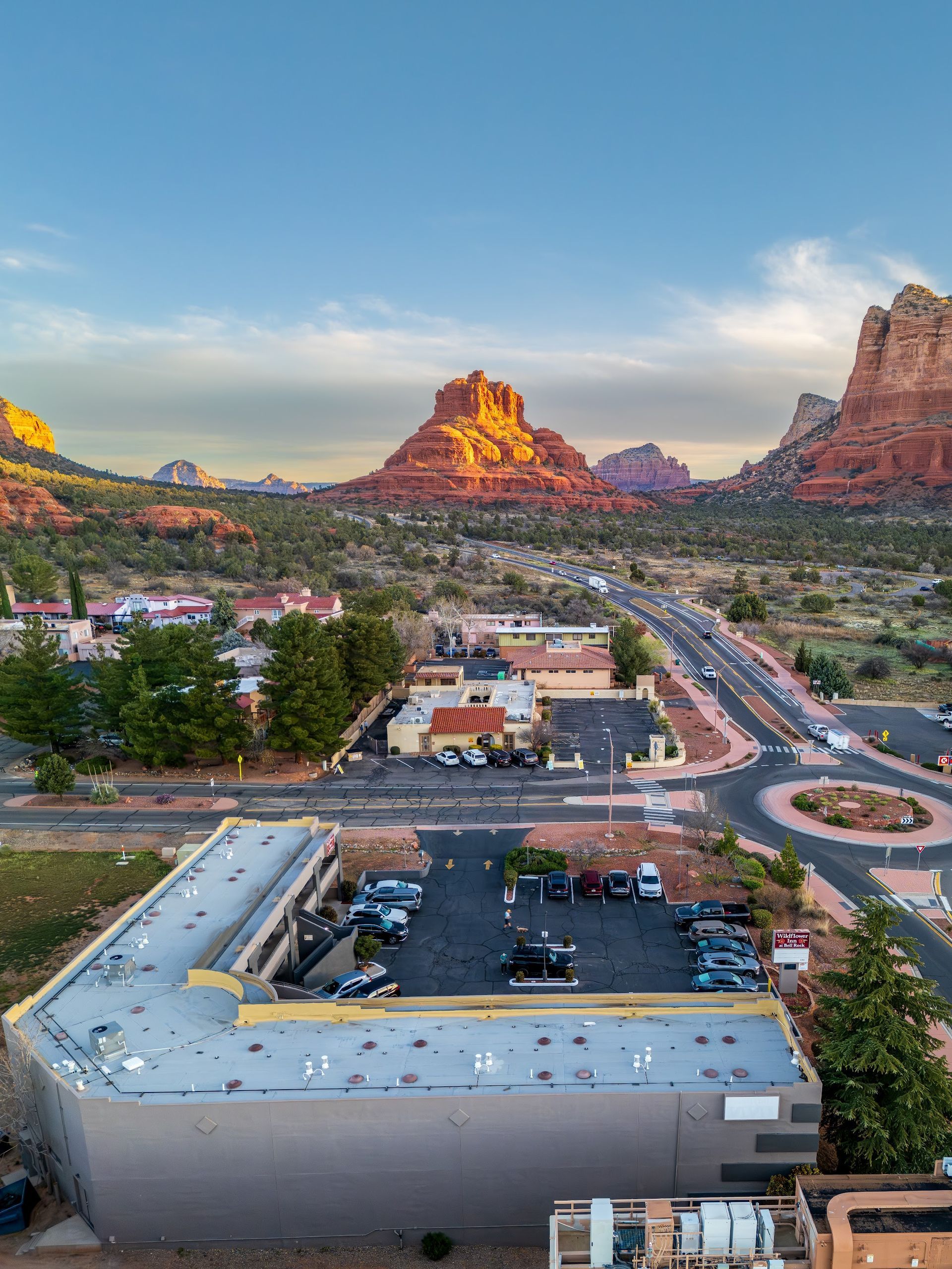 Golden hour aerial of Bell Rock and Courthouse Butte rising above Wildflower Inn at Bell Rock in Village of Oak Creek