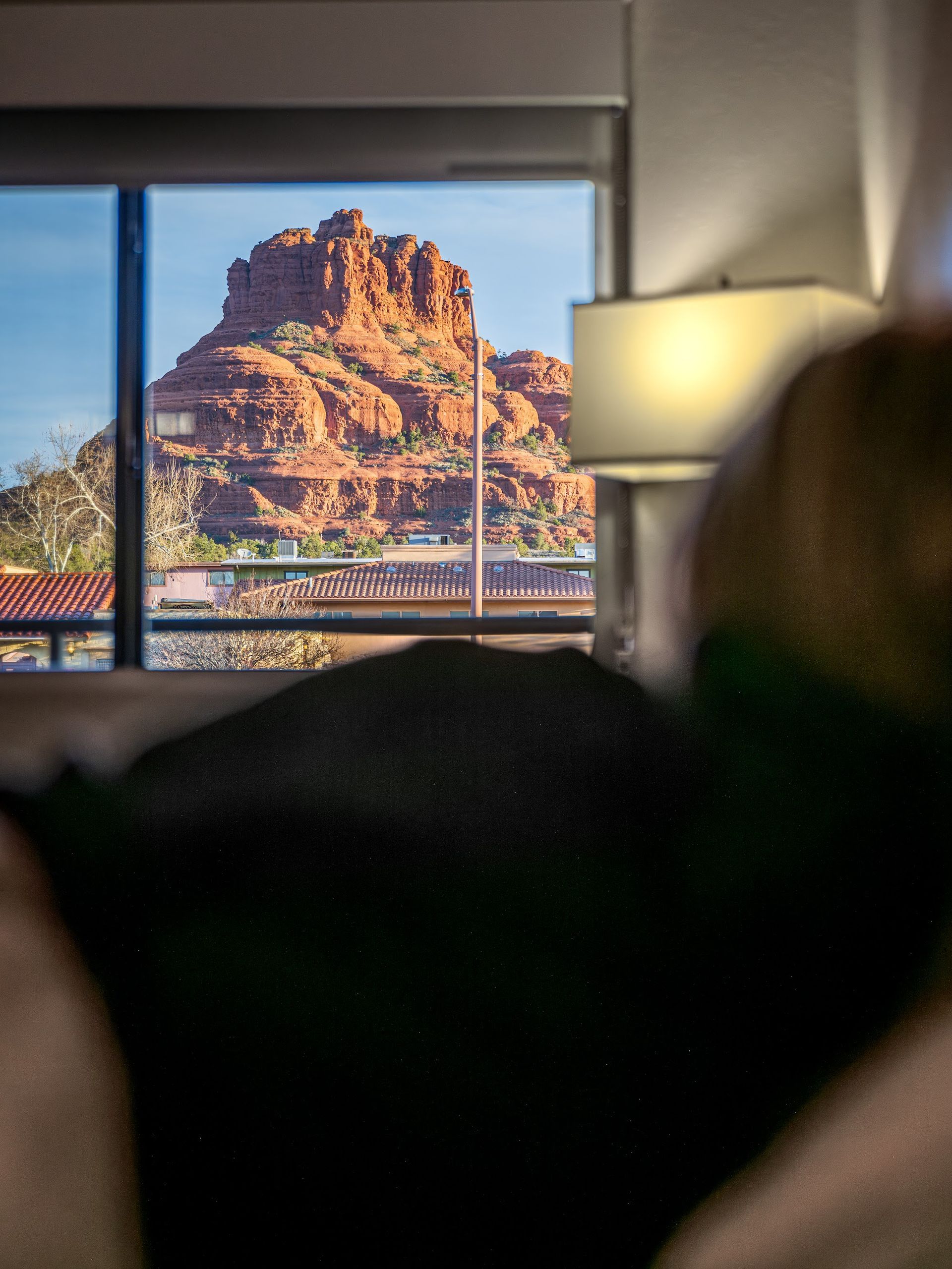 Guest looking out a guest room window at Bell Rock rising above Village of Oak Creek from Wildflower Inn at Bell Rock