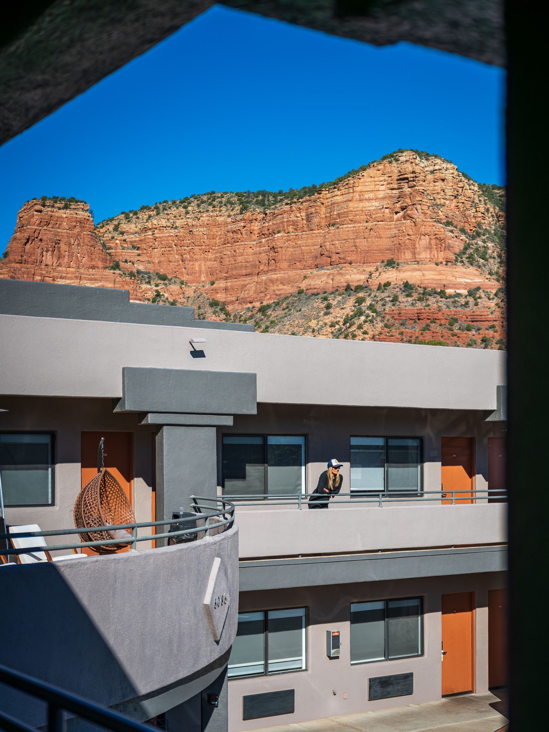 Guest standing on the outdoor walkway at Wildflower Inn at Bell Rock with red rock cliffs rising behind the property