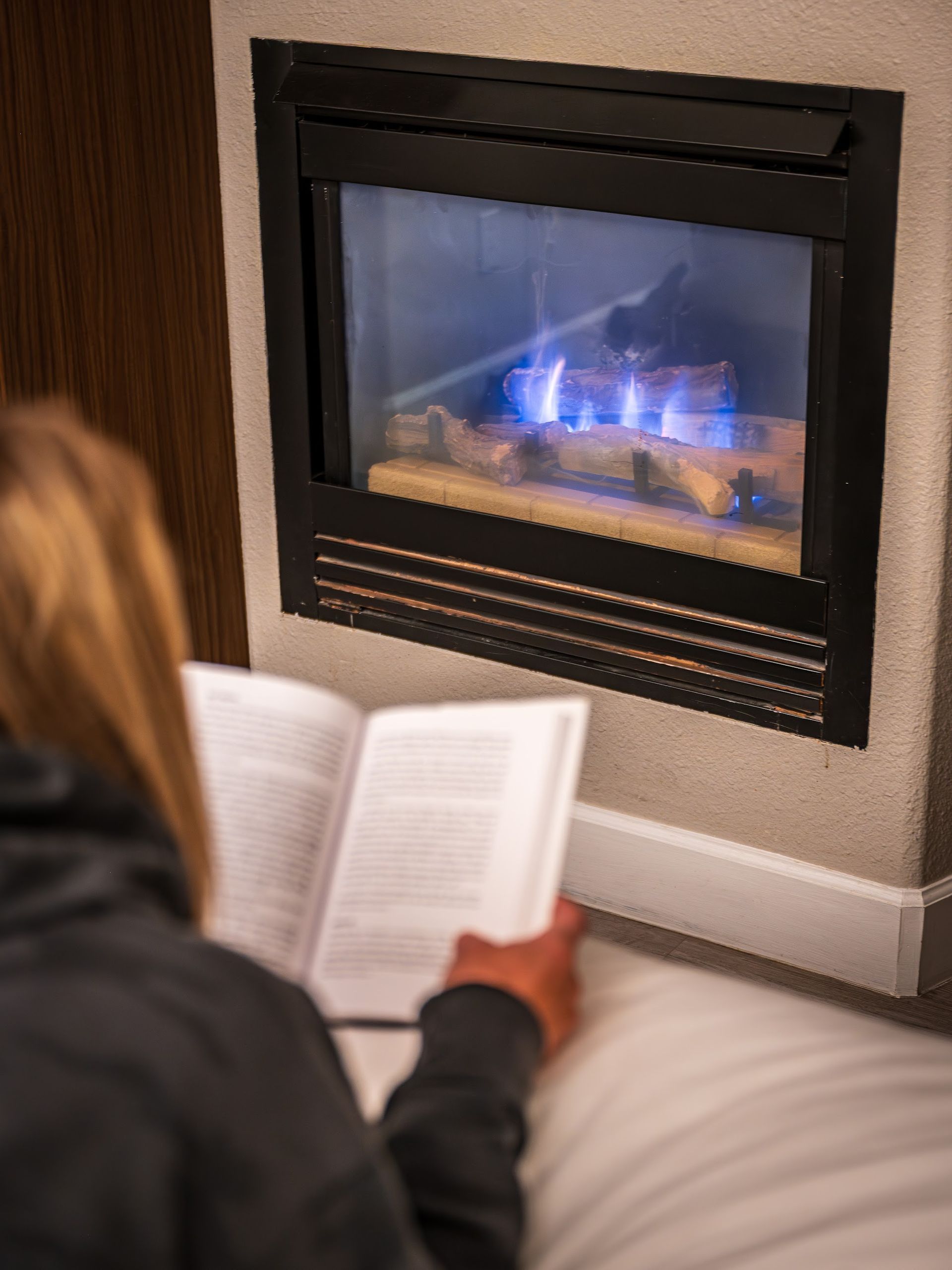 Guest reading a book beside the in-room fireplace at Wildflower Inn at Bell Rock after an evening of stargazing in Sedona