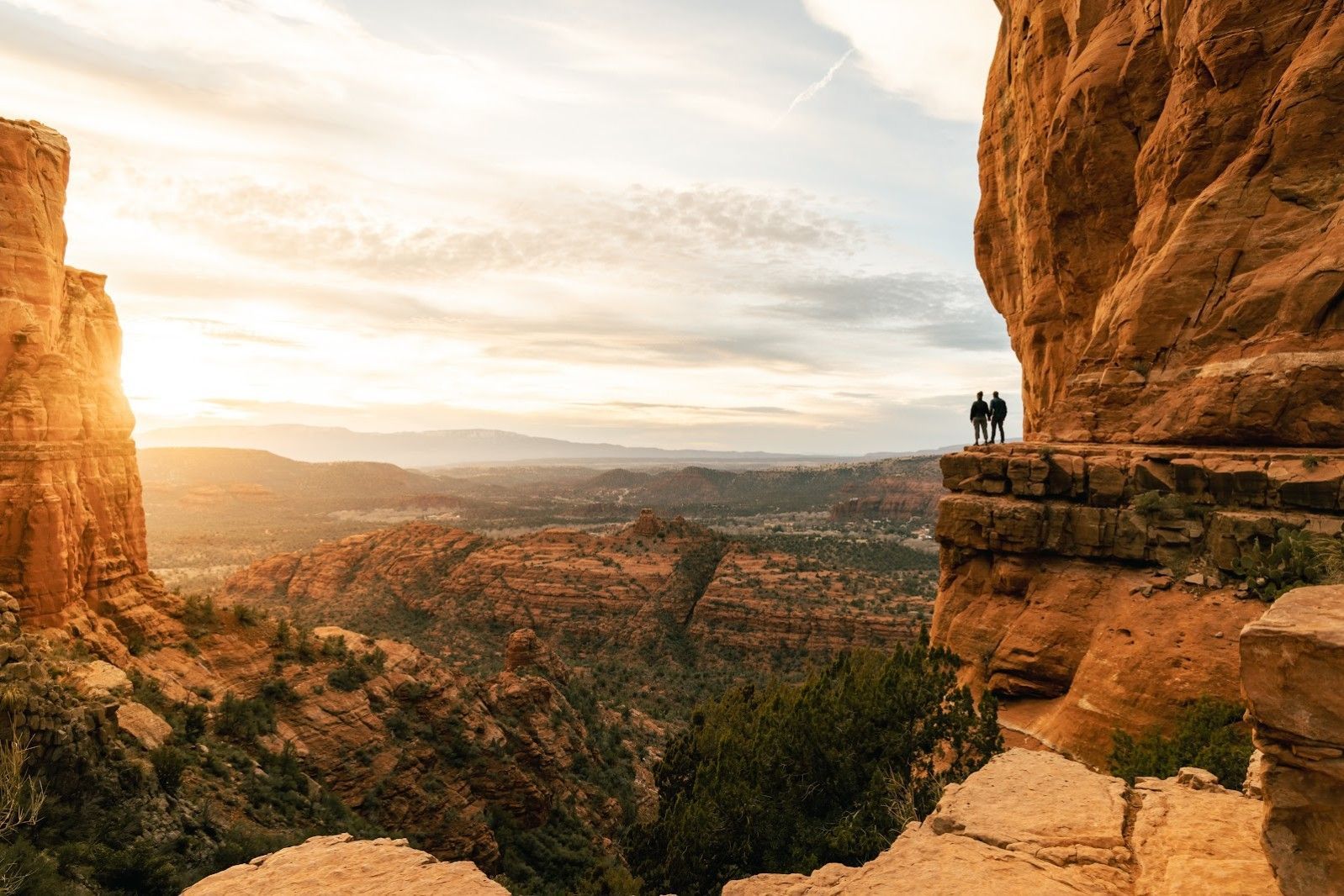 Two people watching the sunset from a red rock overlook in Sedona