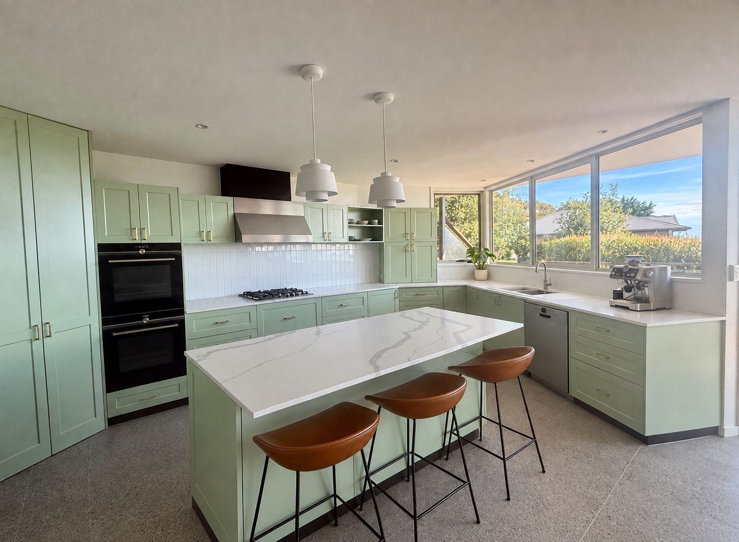 Bright mint-green kitchen with white island, three stools, and large corner windows.
