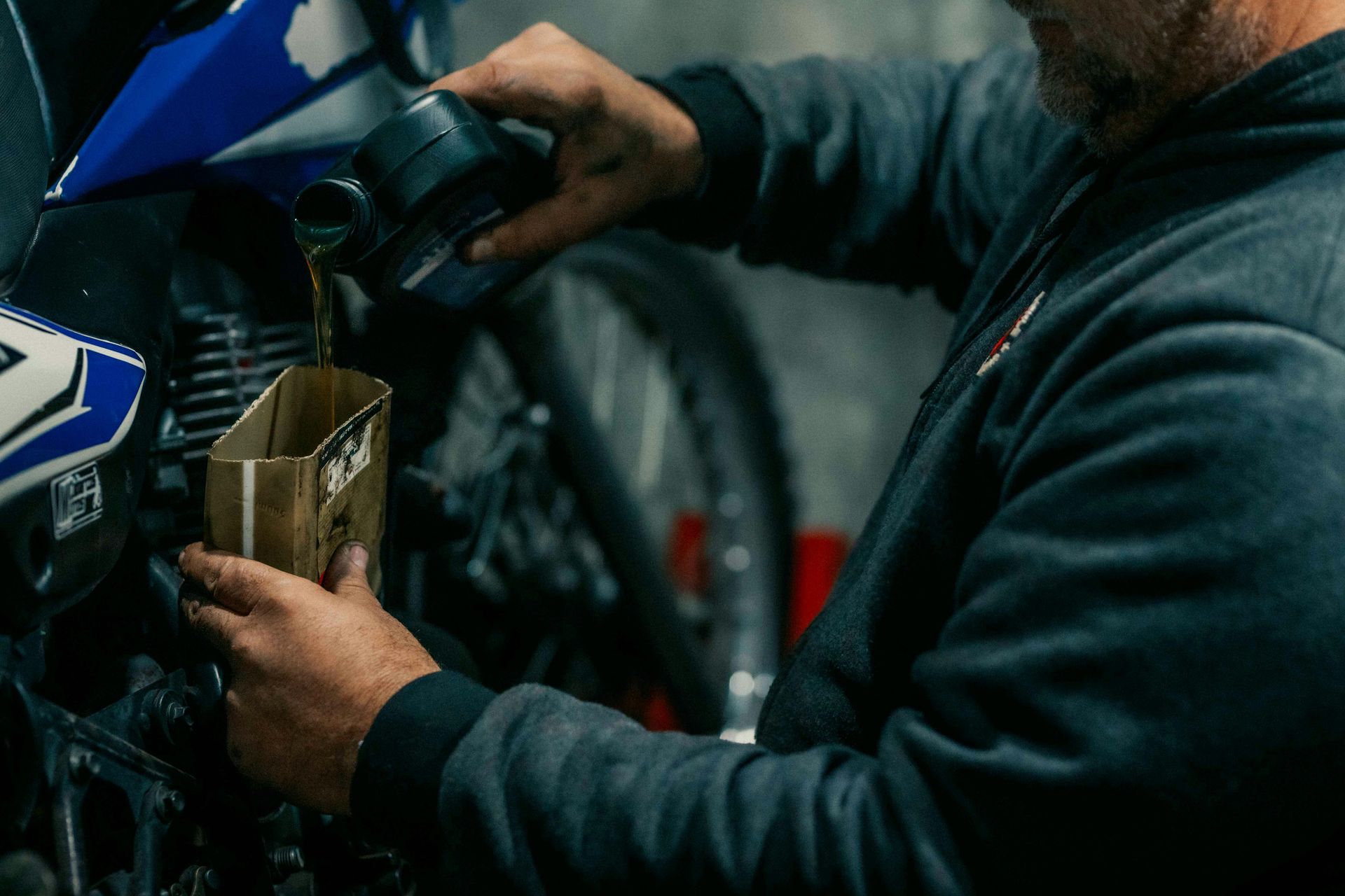 A man pouring oil into a motorcycle.