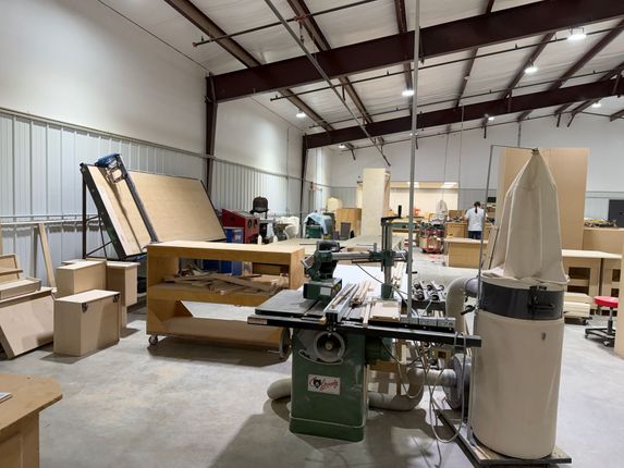 Woodworking shop with saws, lumber, and covered equipment in a large industrial room