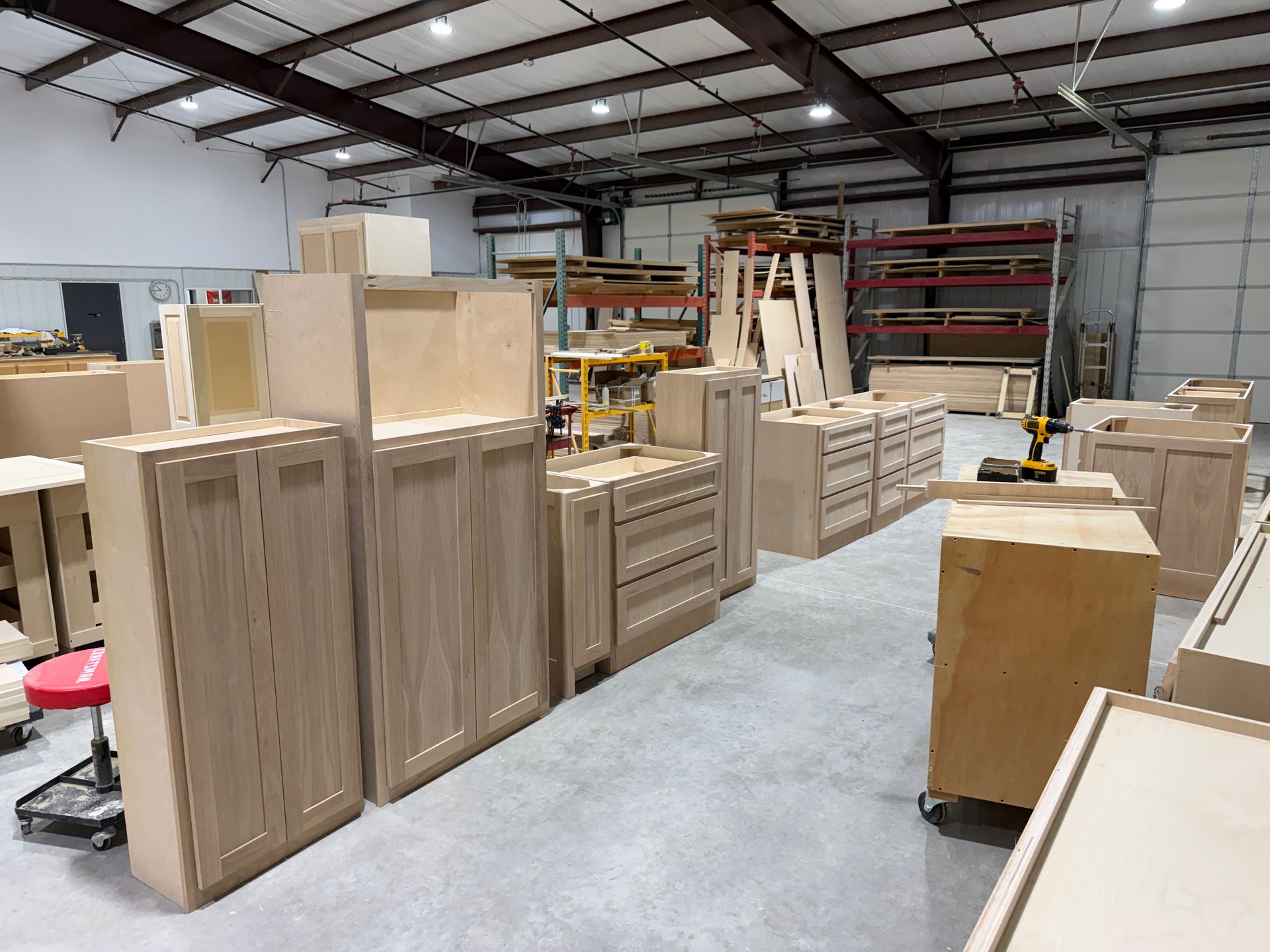 Wooden cabinets and drawers arranged in a workshop warehouse with metal shelving and open space