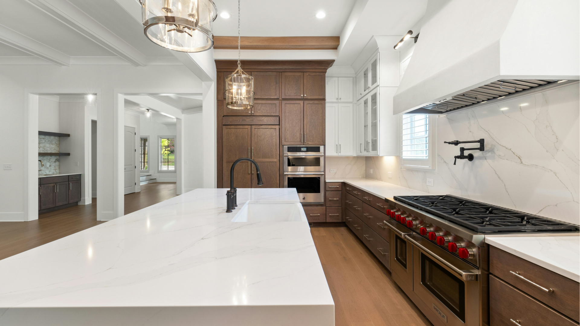 Modern white and wood kitchen with large island, stainless range, and marble backsplash