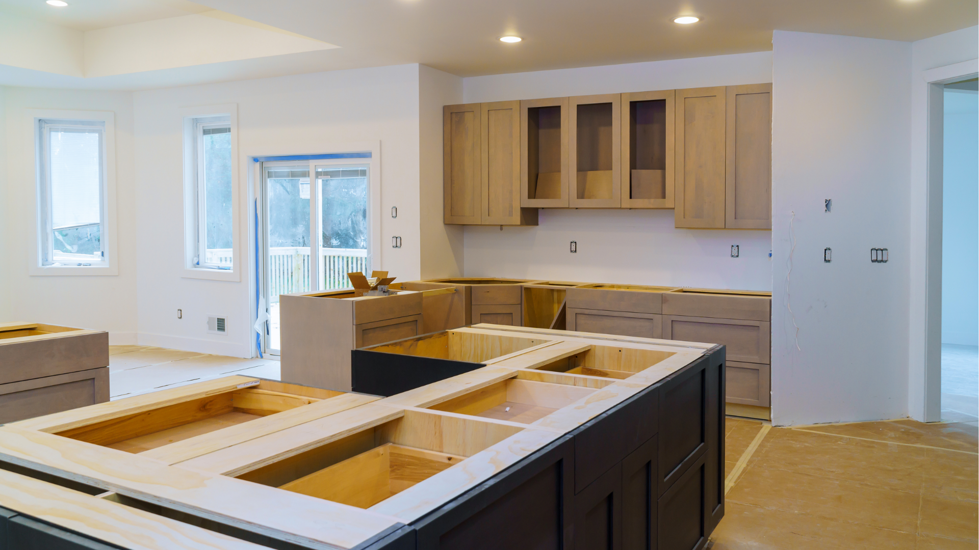 Bright modern kitchen with white walls, wood cabinets, and a large island under construction