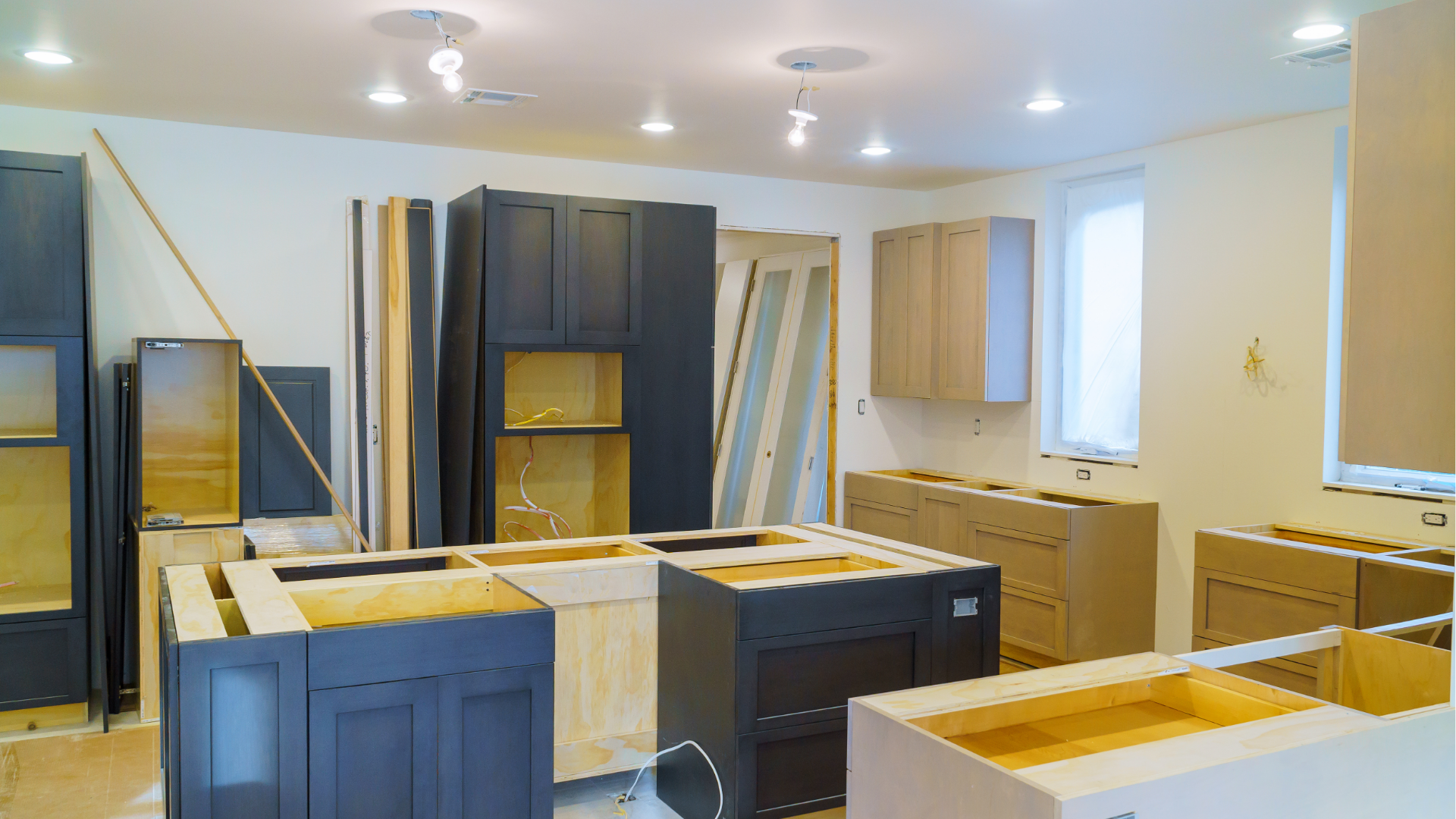 Kitchen cabinets being installed in a bright room during renovation