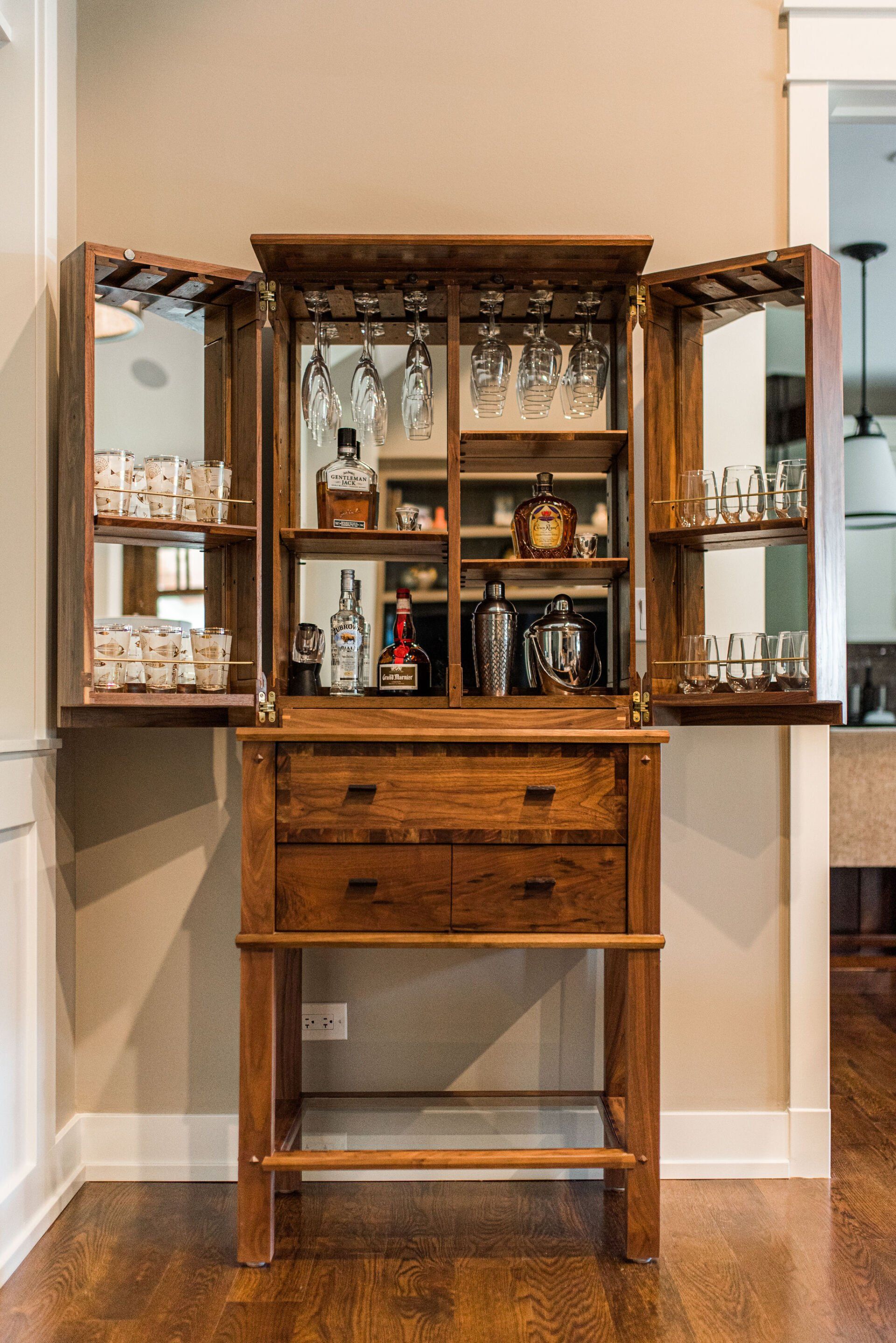 A small wooden bar with glasses , bottles , and a mirror.