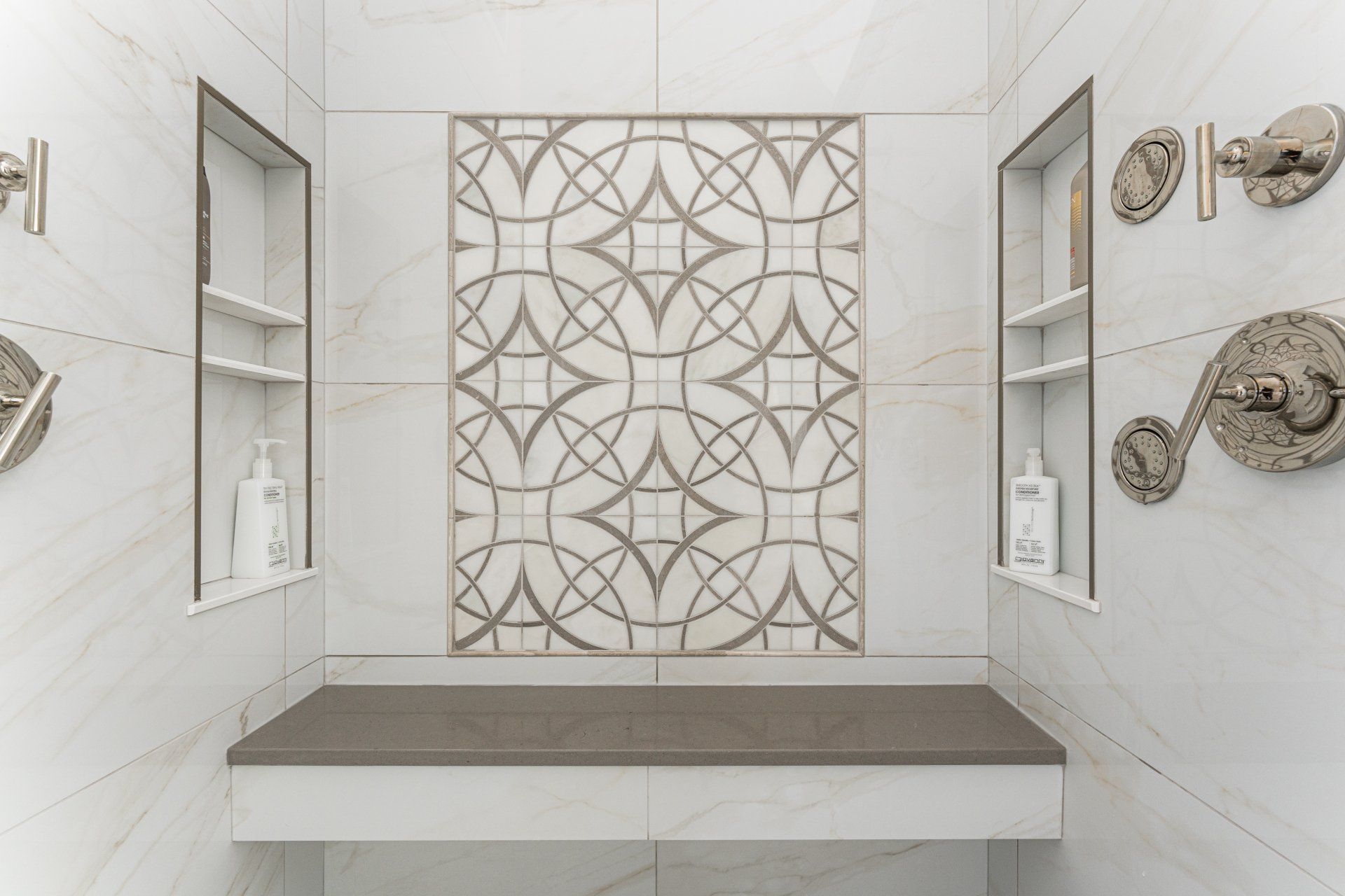 A bathroom with a bench and a shower with a pattern on the wall.