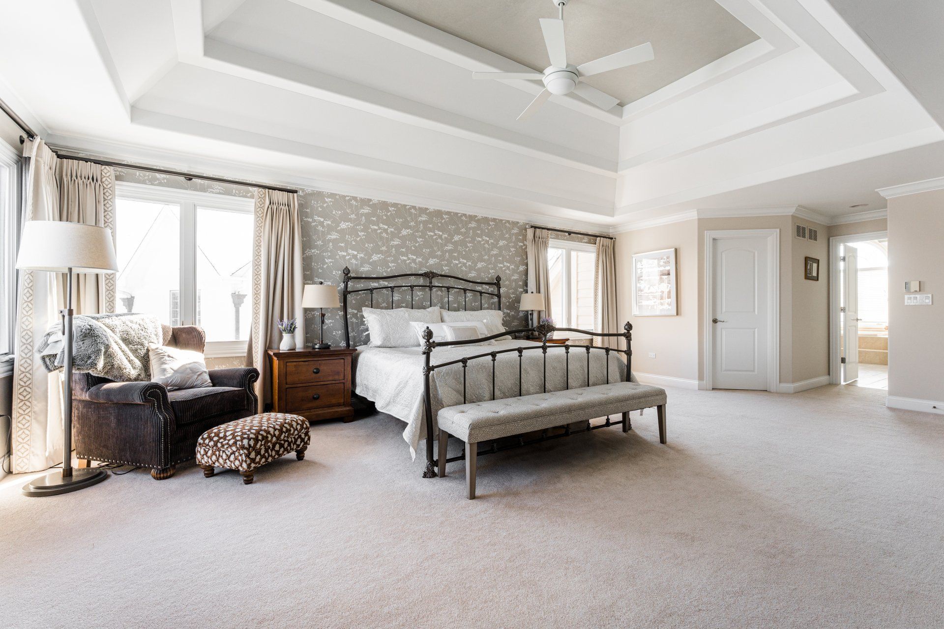 A large bedroom with a ceiling fan and a bed.