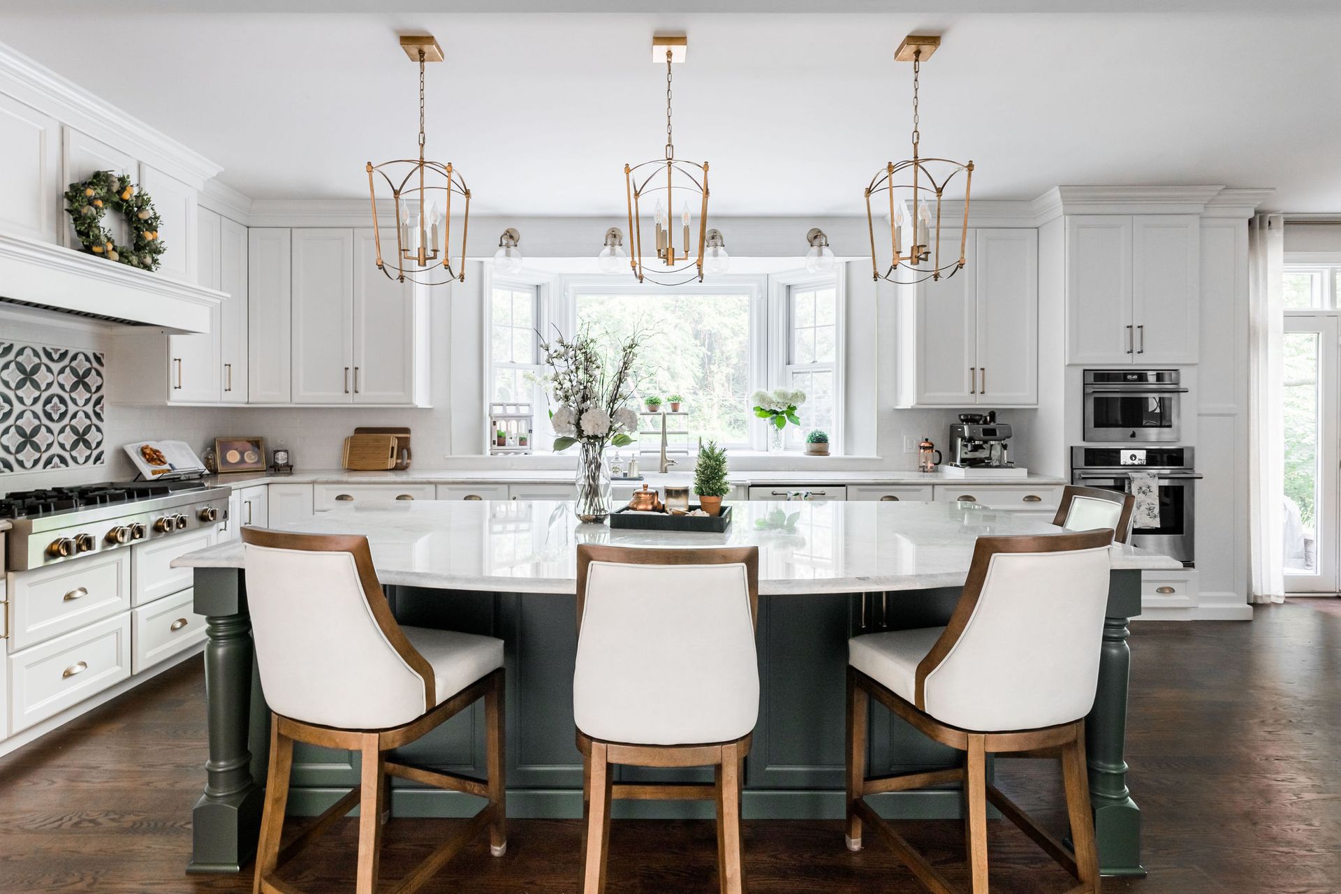 A kitchen with white cabinets , a large island , and three chairs.