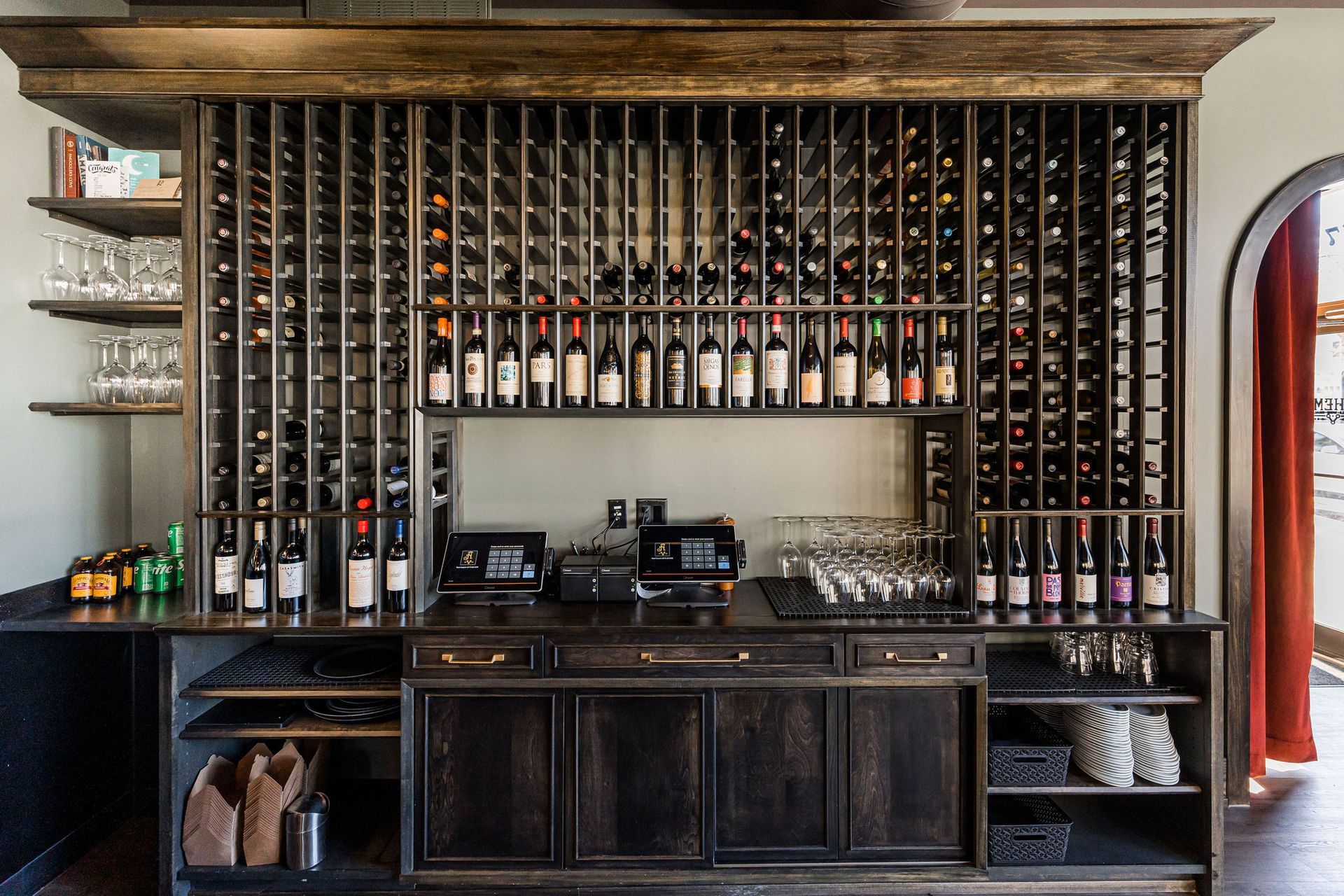 A bar with a lot of wine bottles on the wall.