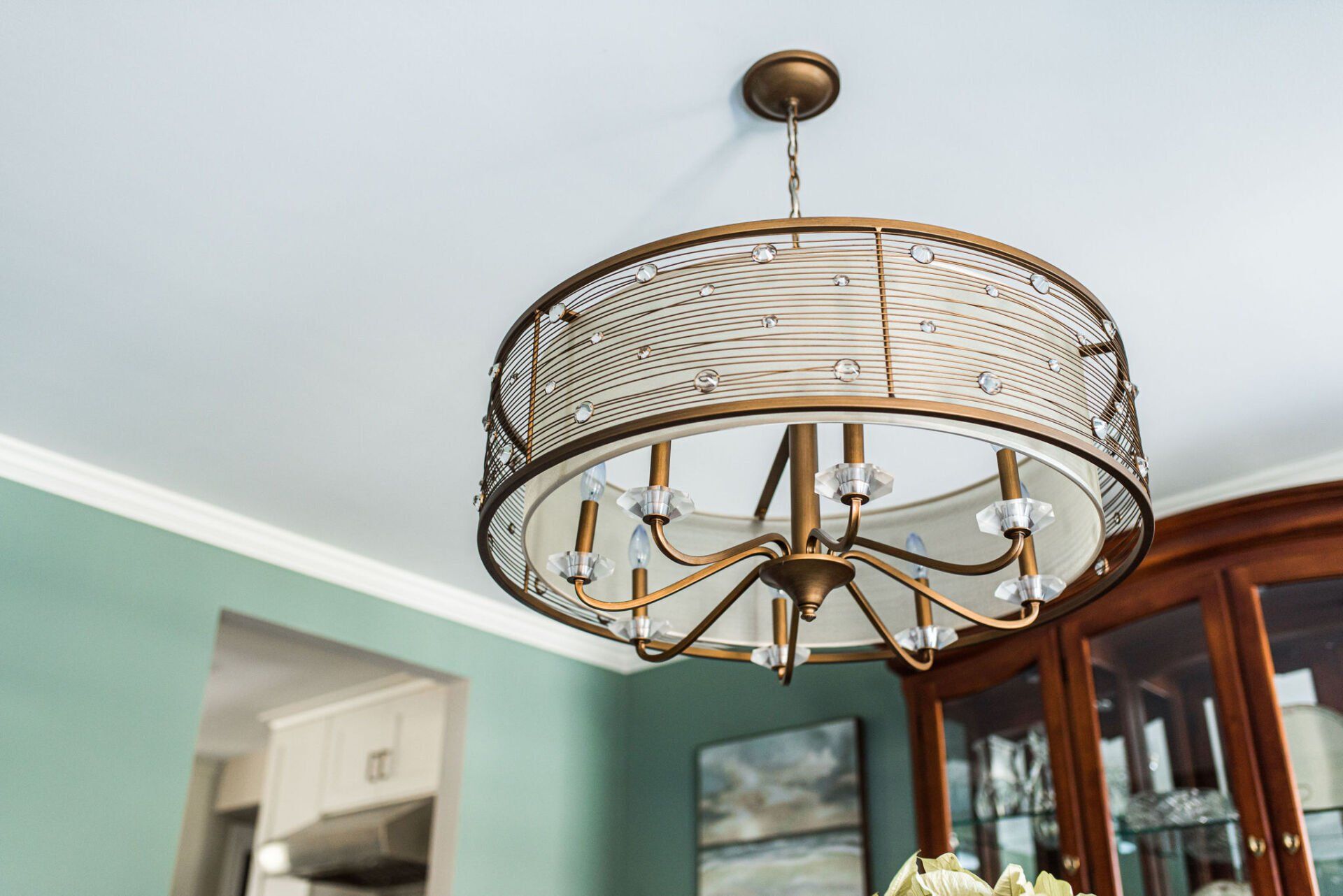 A chandelier is hanging from the ceiling in a dining room.