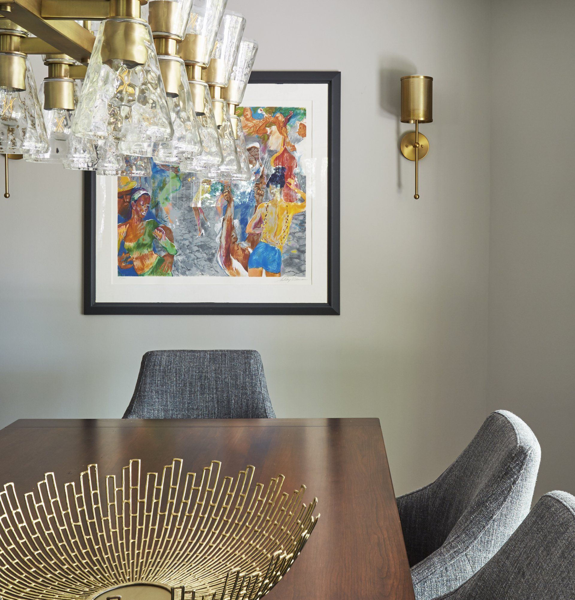A dining room table with a picture on the wall above it