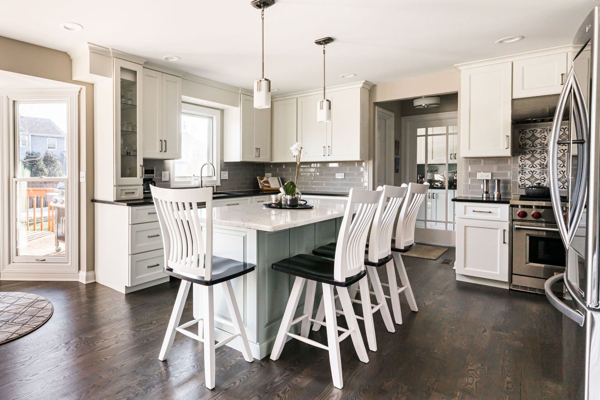 A kitchen with white cabinets , stools and a large island.