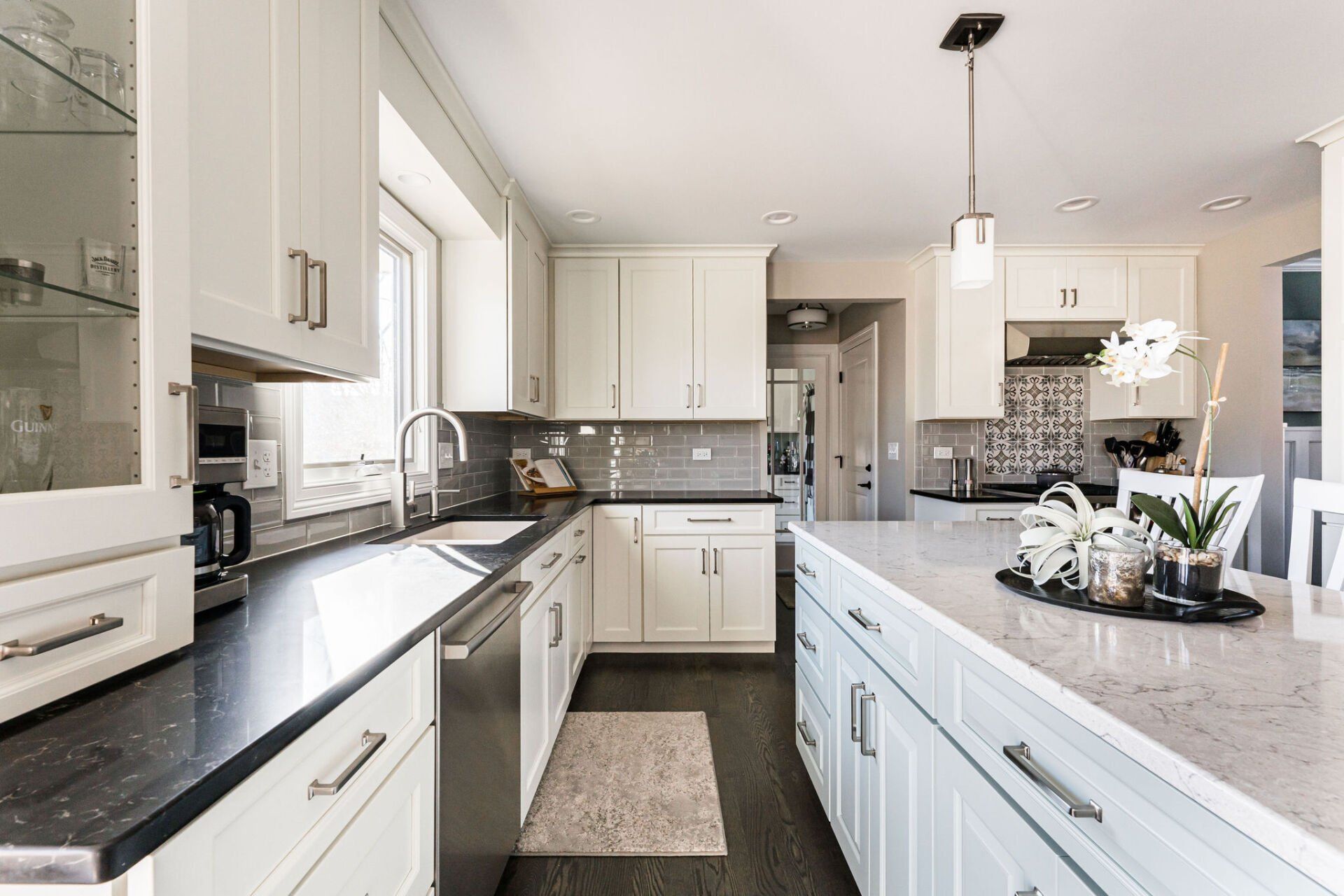A kitchen with white cabinets , black counter tops , and a large island.