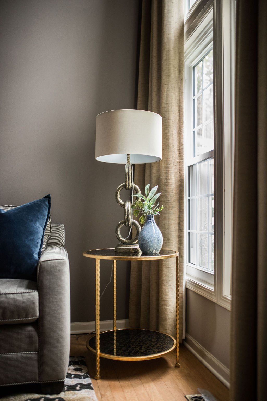 A lamp is sitting on a side table next to a window in a living room.