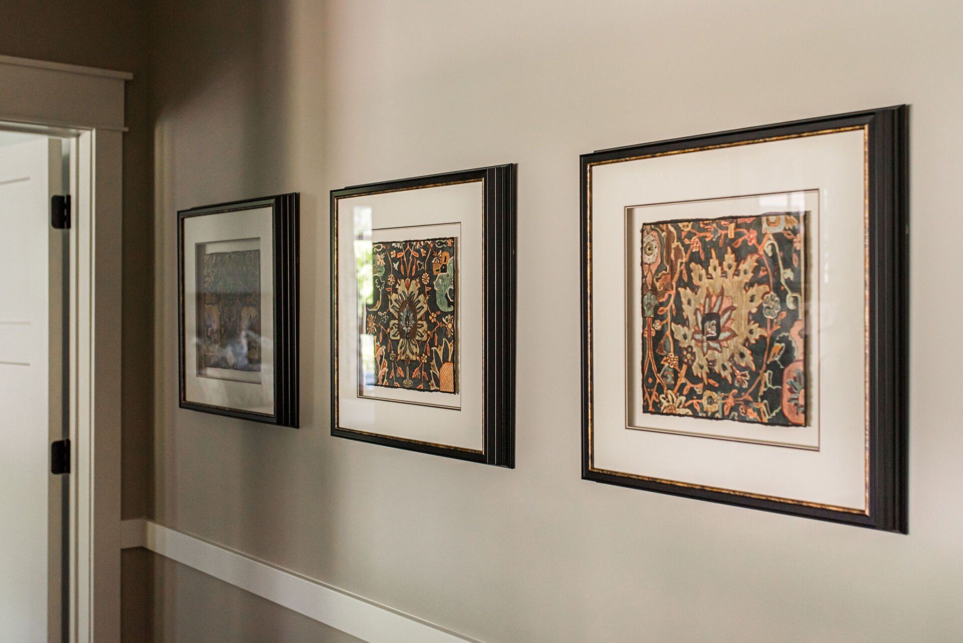 Three framed pictures are hanging on a wall in a hallway.