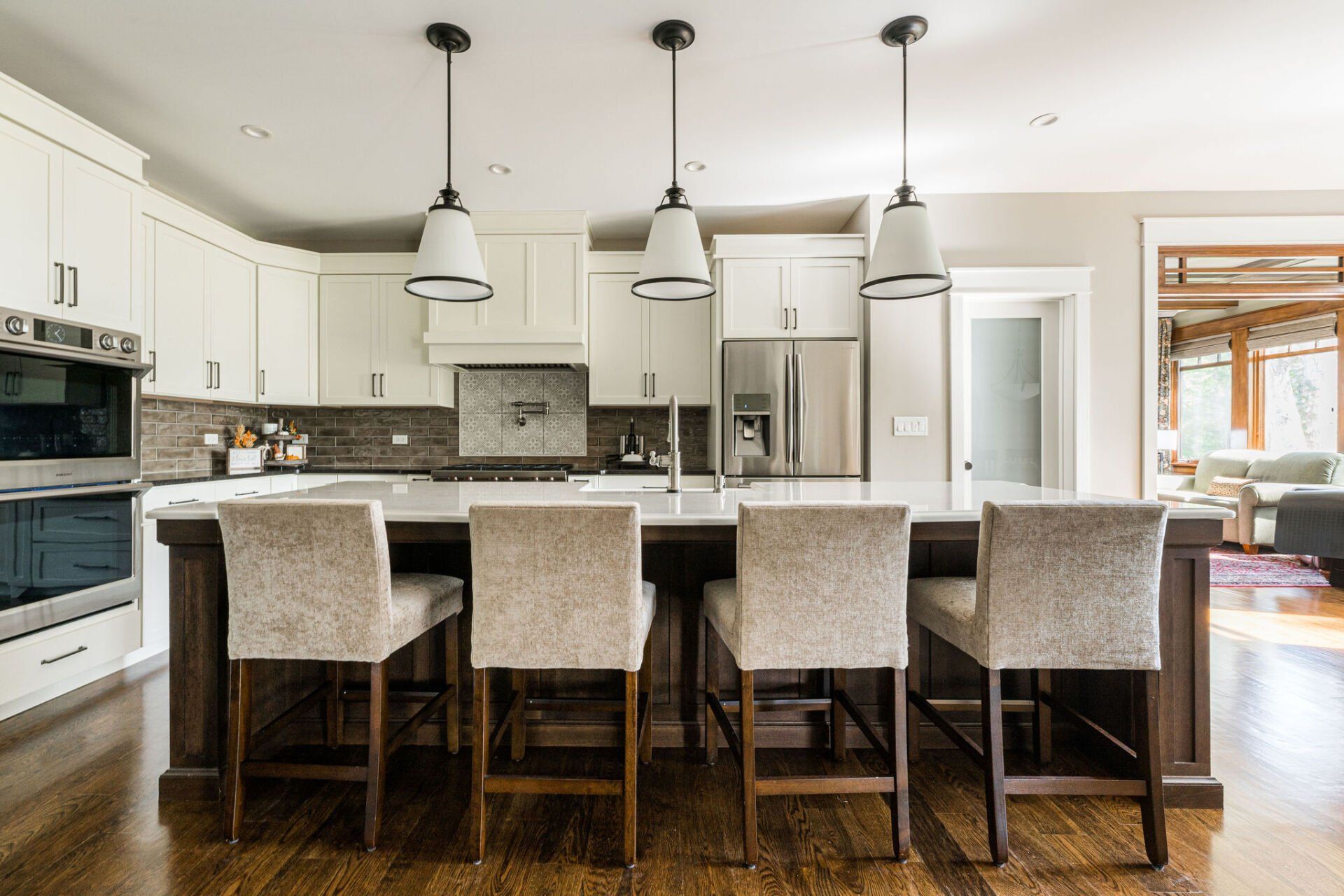 A kitchen with white cabinets , stainless steel appliances , and a large island with stools.