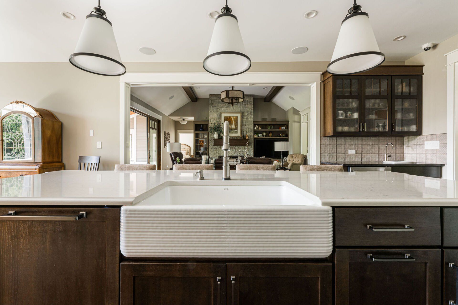 A kitchen with a large white sink and wooden cabinets.