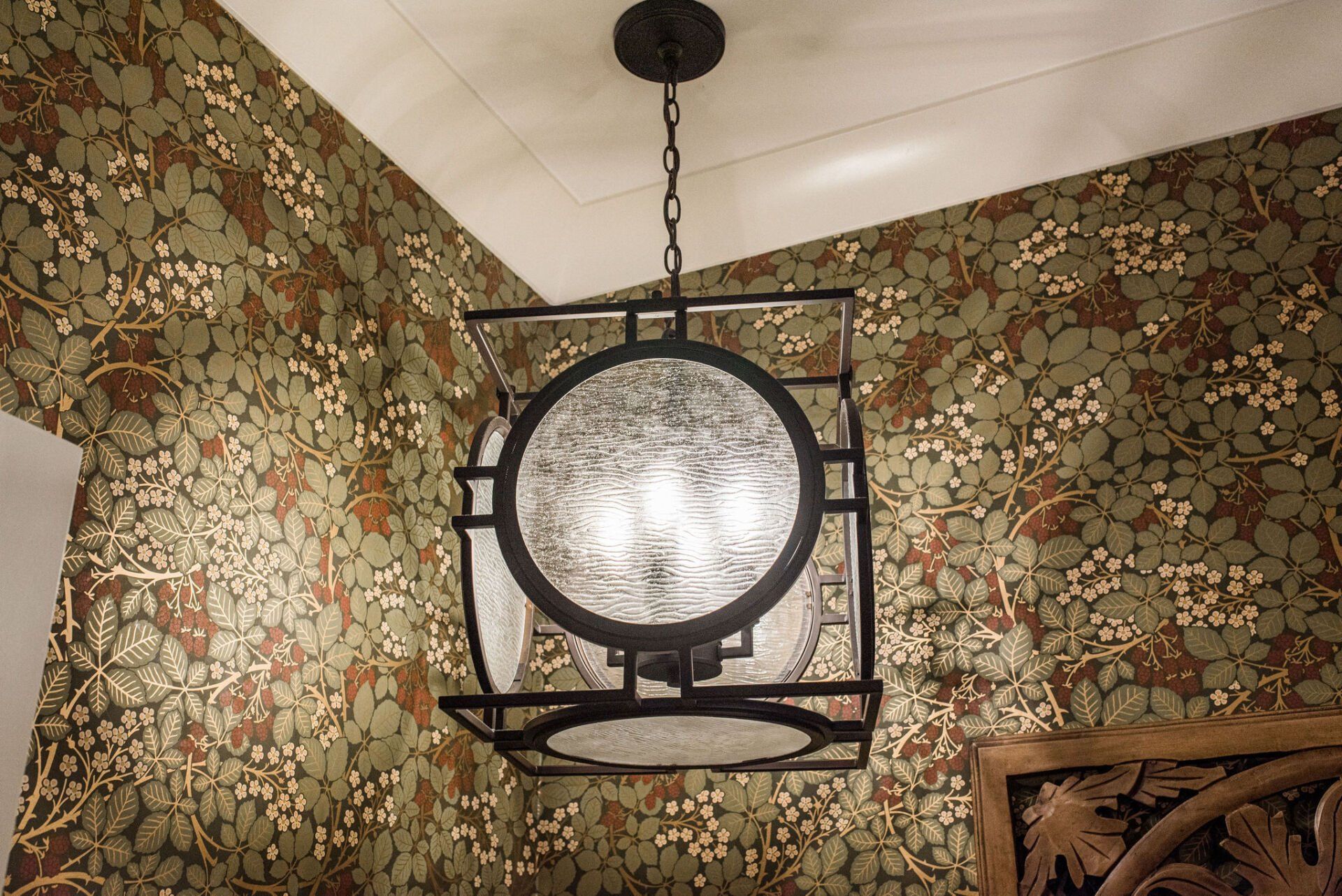A chandelier is hanging from the ceiling in a room with floral wallpaper