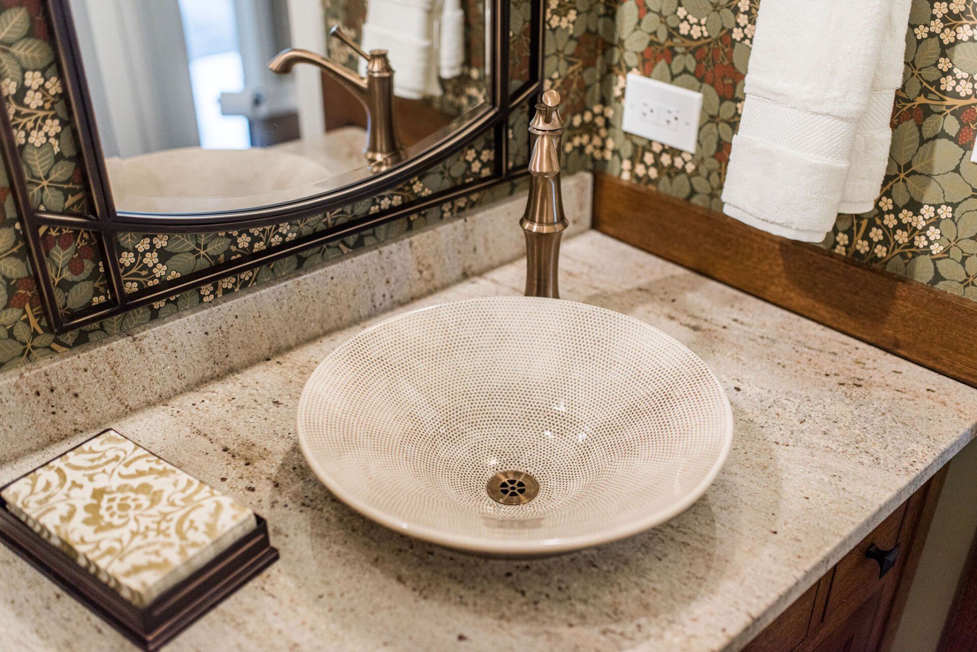 A bathroom with a sink , mirror , and towels.
