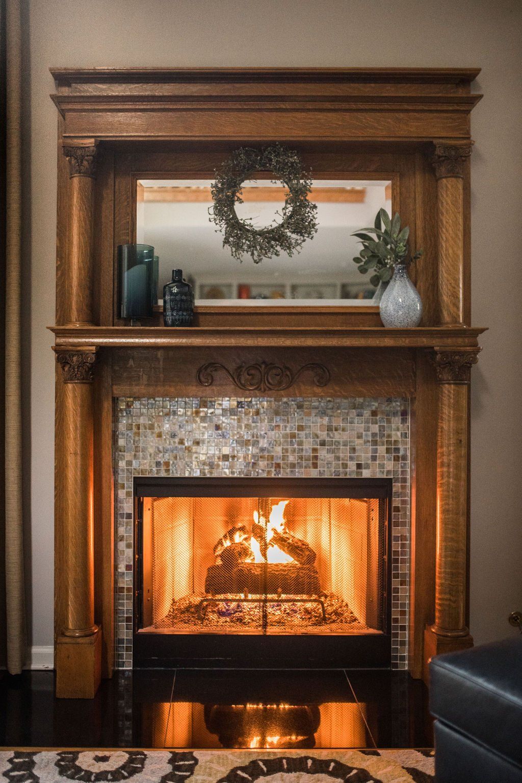 A living room with a fireplace and a wreath on the mantle.