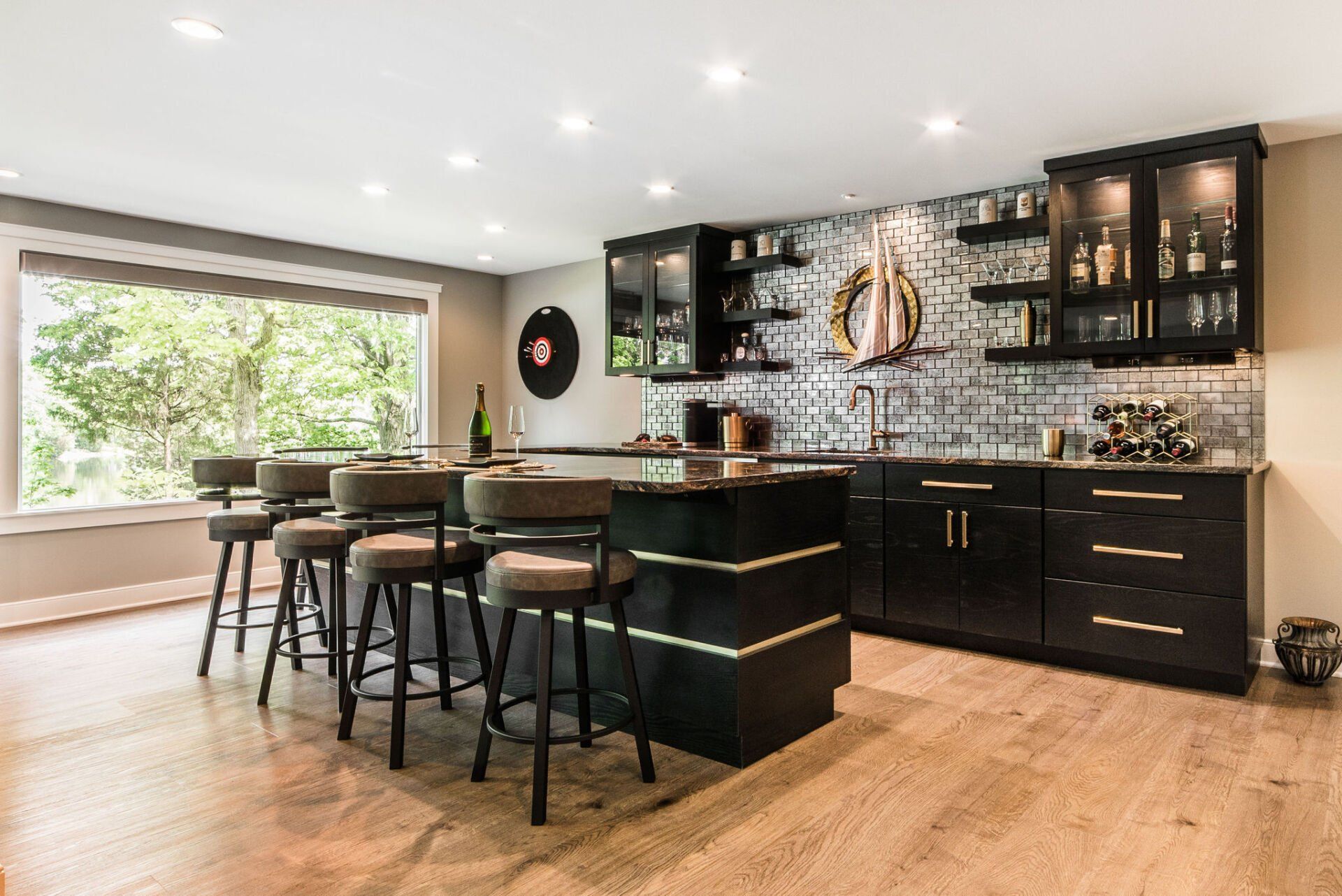 A kitchen with a bar and stools and a large window.